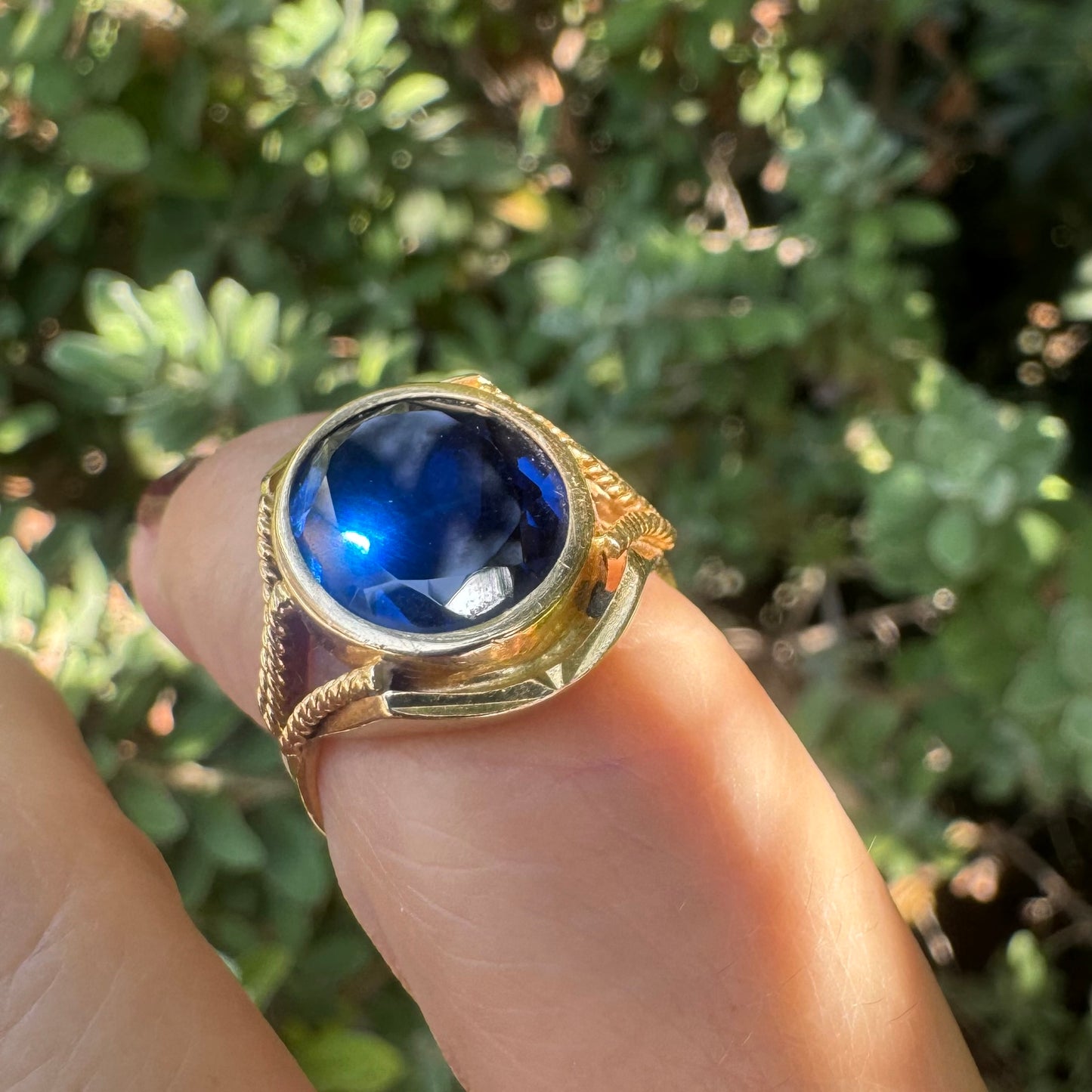 18K yellow gold ring set with a large oval deep blue Sapphire set in an ornate bezel.