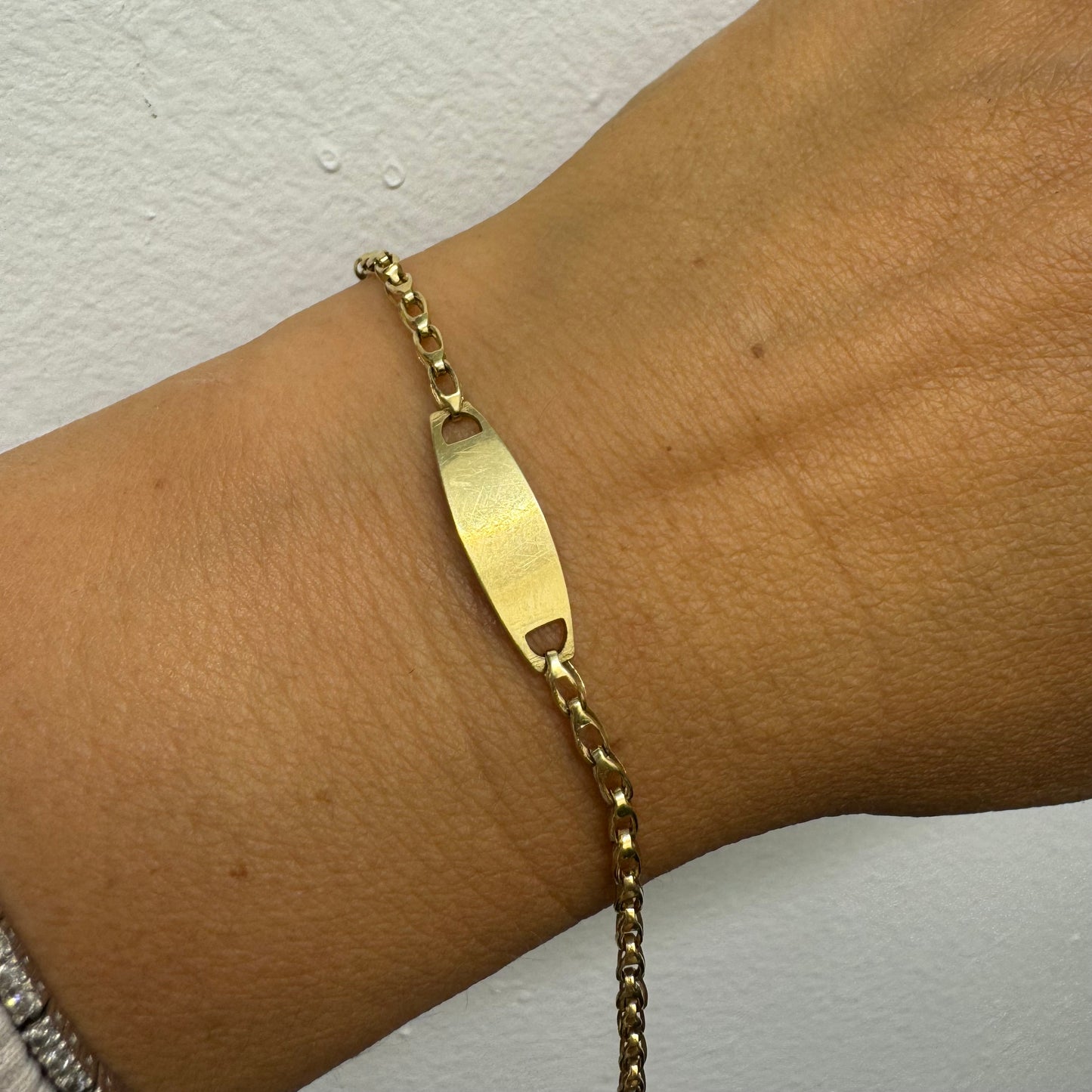 14K gold bracelet featuring a smooth ID plate and a delicate classic chain.