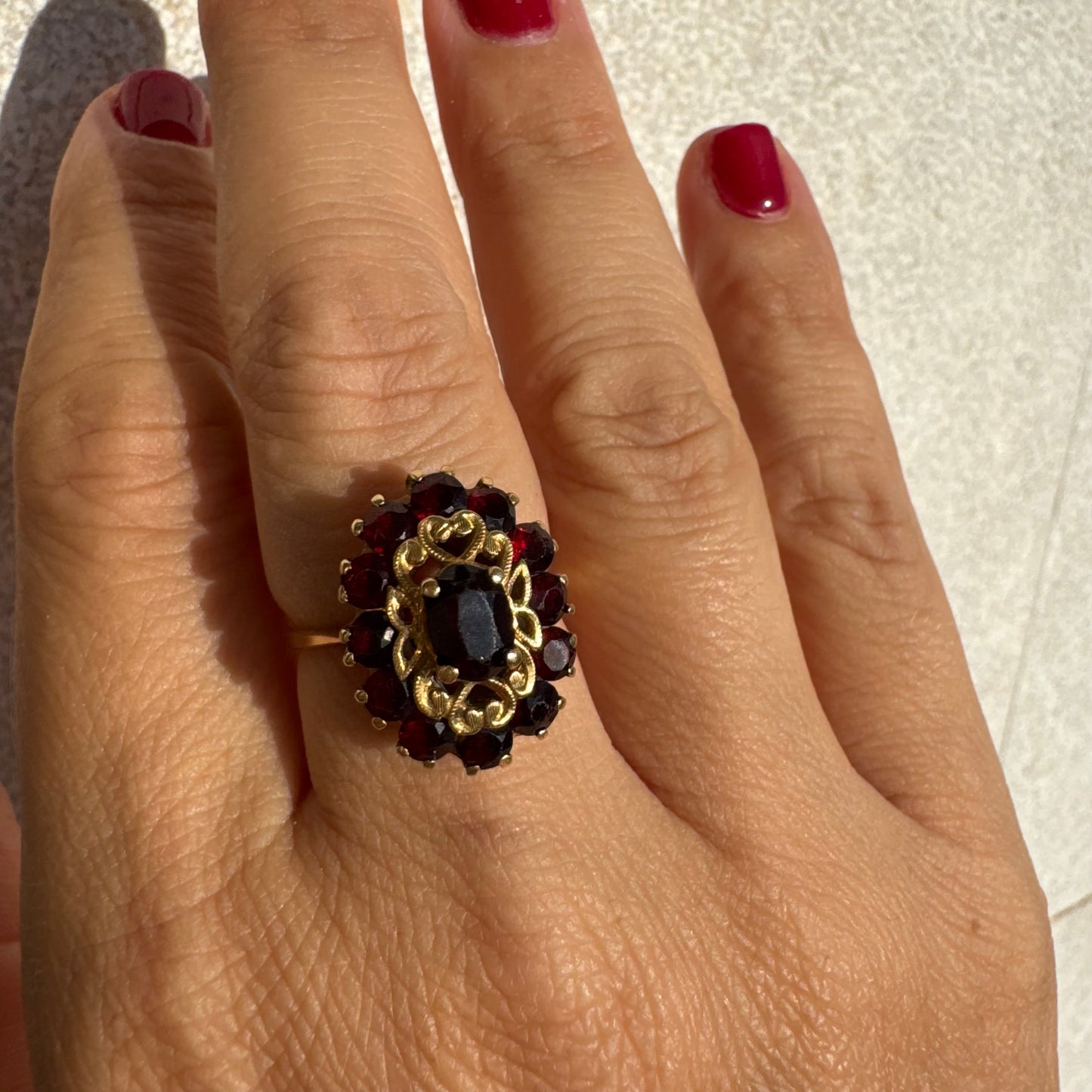 18K gold ring adorned with deep red Garnet gemstones, arranged in a radiant oval composition
