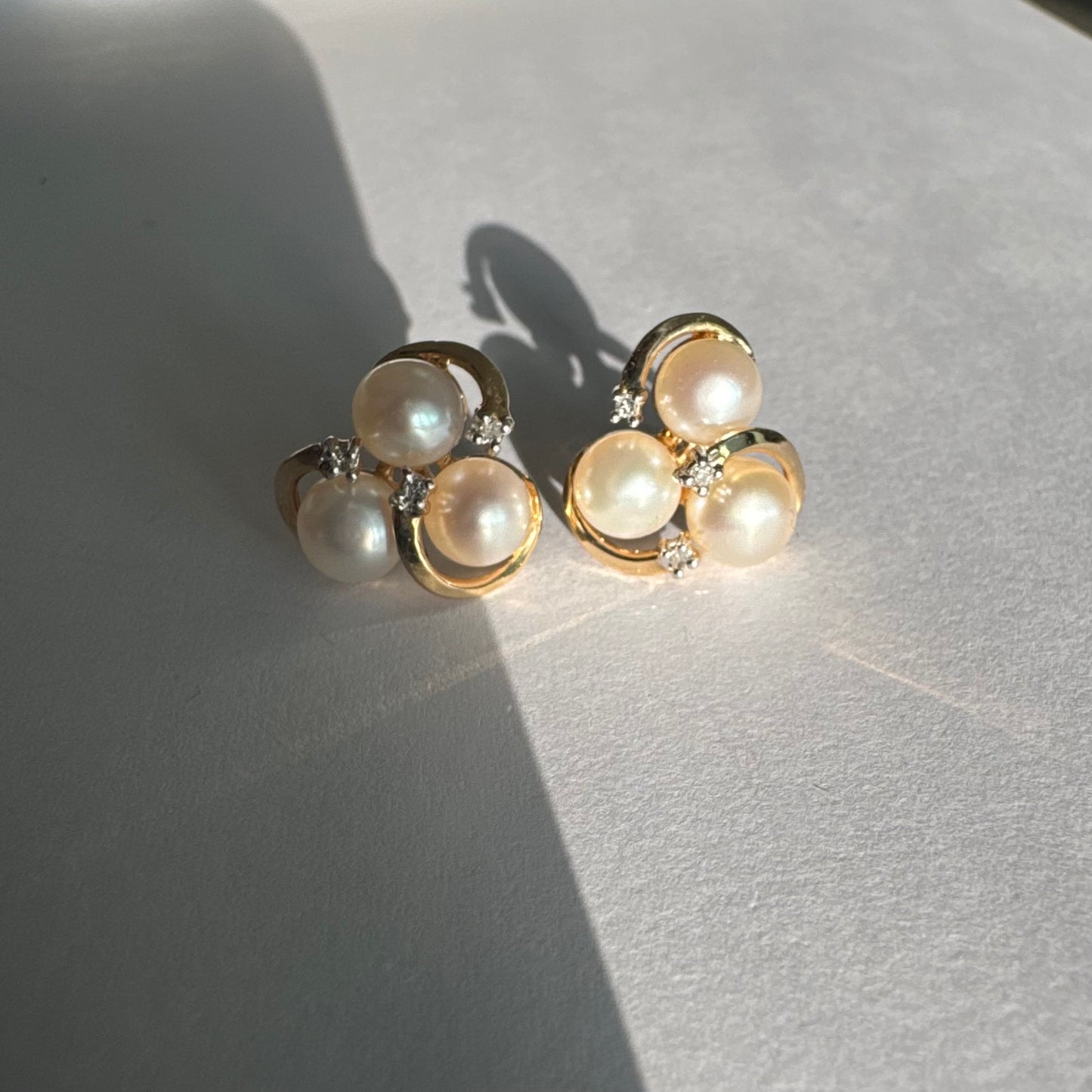 10K gold stud earrings in a delicate floral design, set with three creamy natural Pearls & Diamonds.