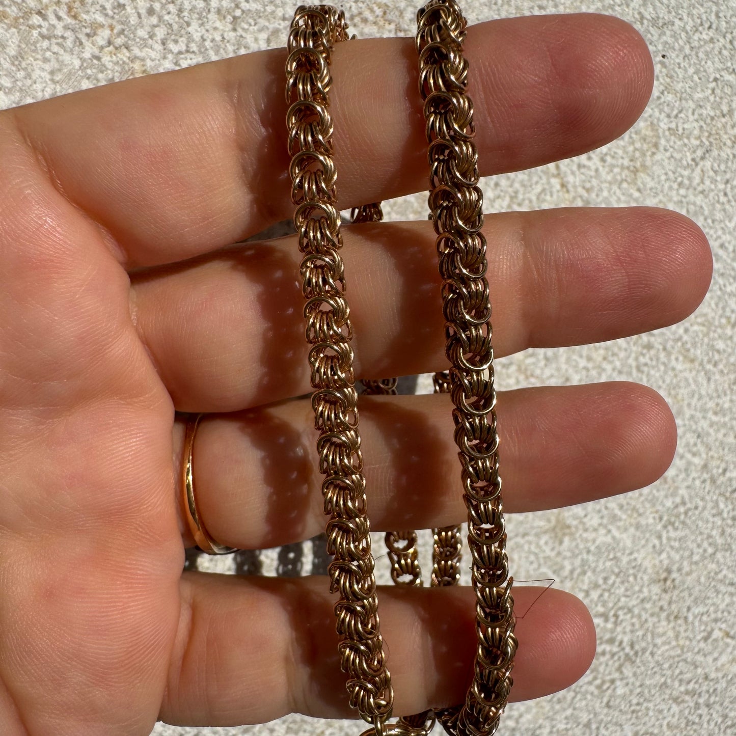 14K gold necklace featuring intricate, interwoven links that create a rich and textured look.