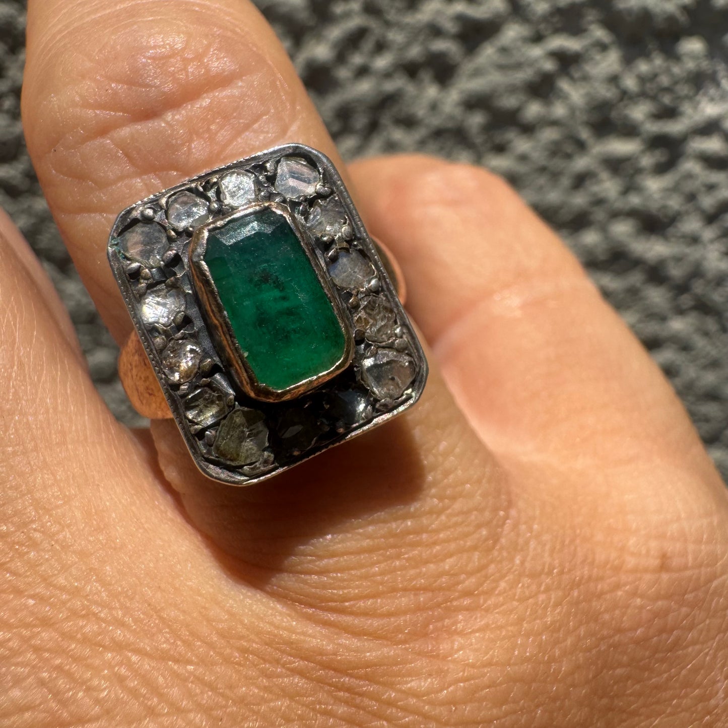 18K gold ring set with a rectangular Emerald and framed by a halo of rose-cut Diamonds