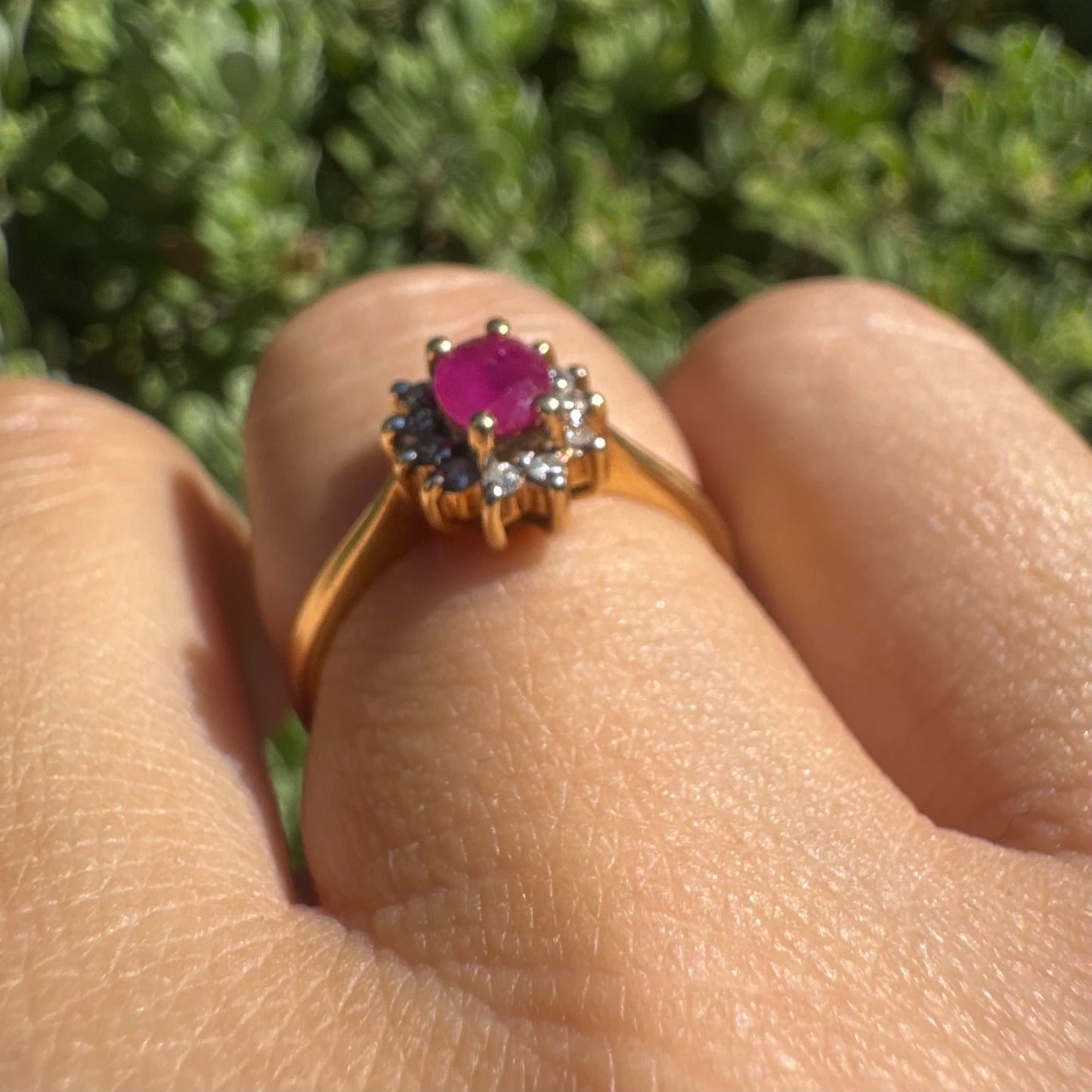 18K gold ring set with an oval Ruby at the center, surrounded by a halo of Diamonds