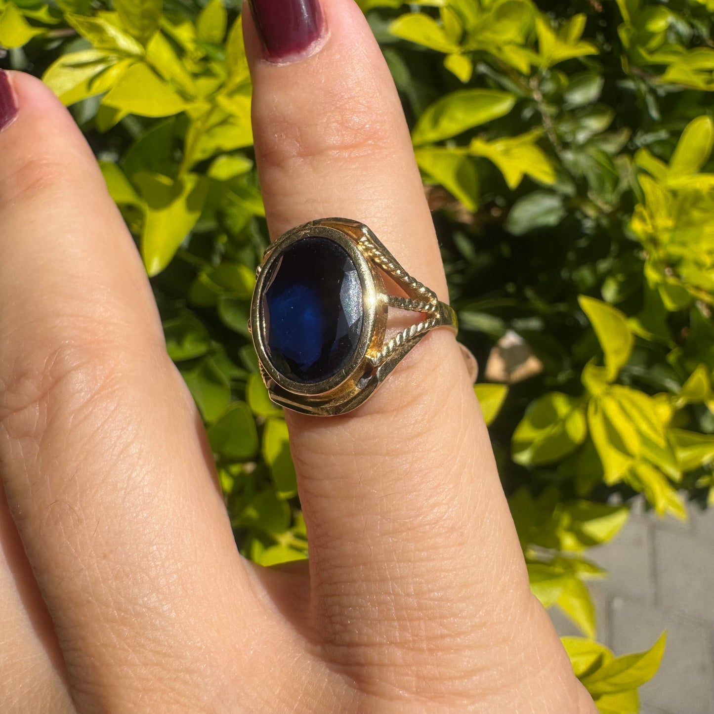 18K yellow gold ring set with a large oval deep blue Sapphire set in an ornate bezel.