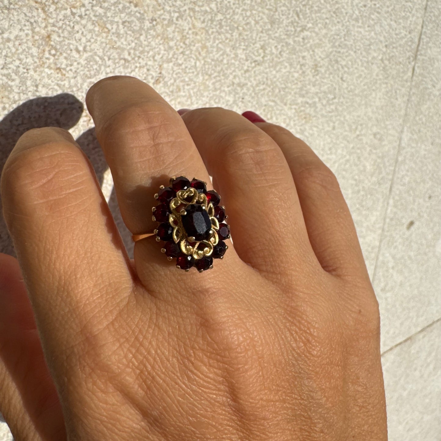 18K gold ring adorned with deep red Garnet gemstones, arranged in a radiant oval composition