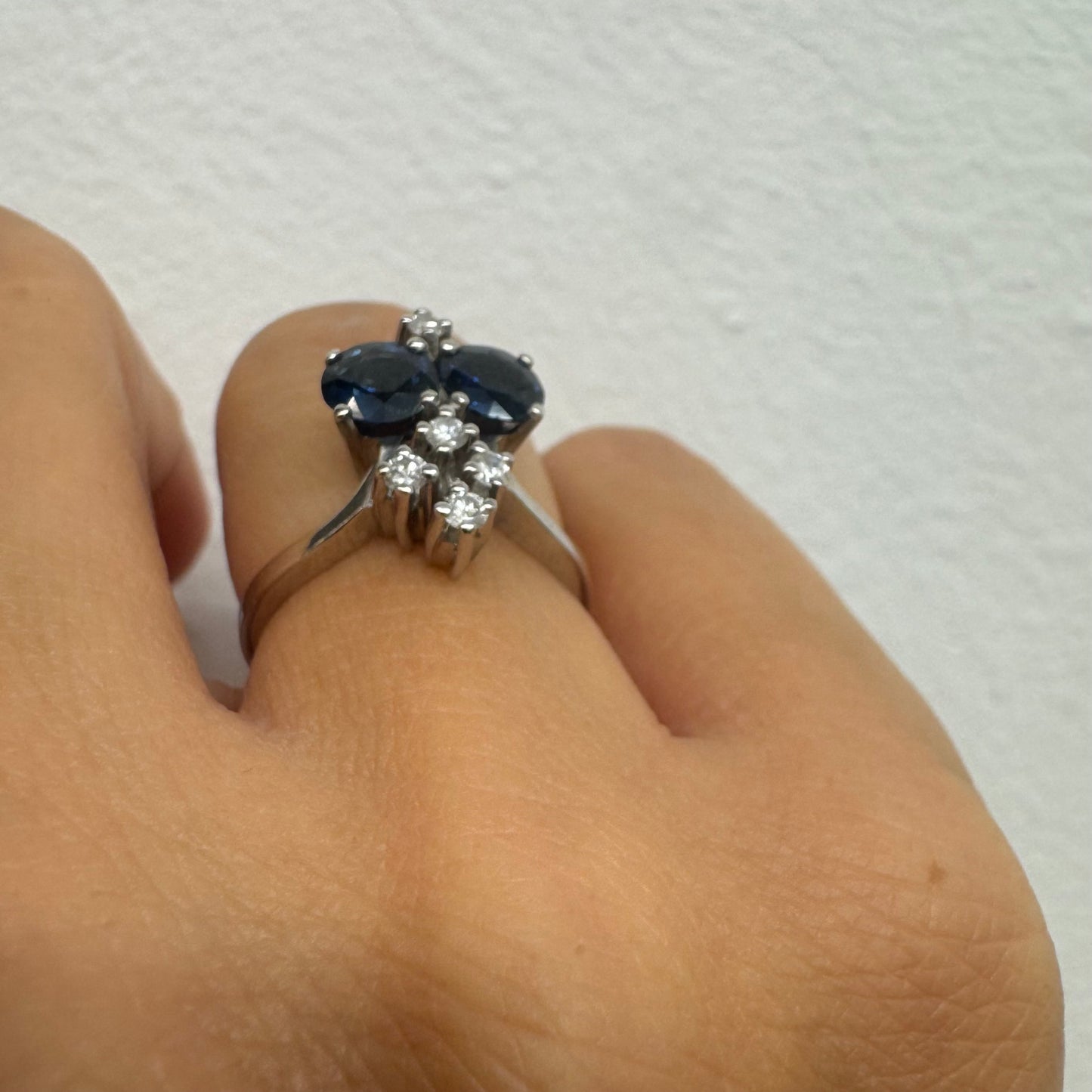 14K gold ring set with two deep blue oval Sapphires accented by clusters of brilliant white Diamonds.