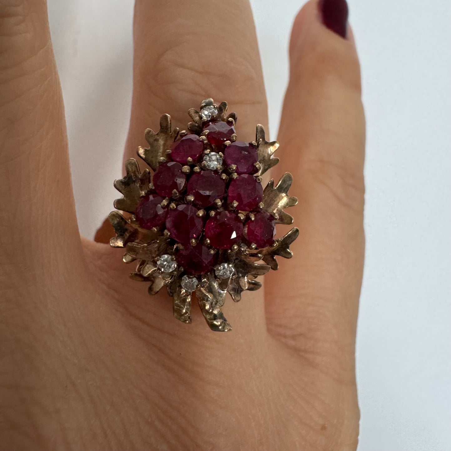 14K gold ring set with a vibrant cluster of deep red rubies and sparkling diamonds.