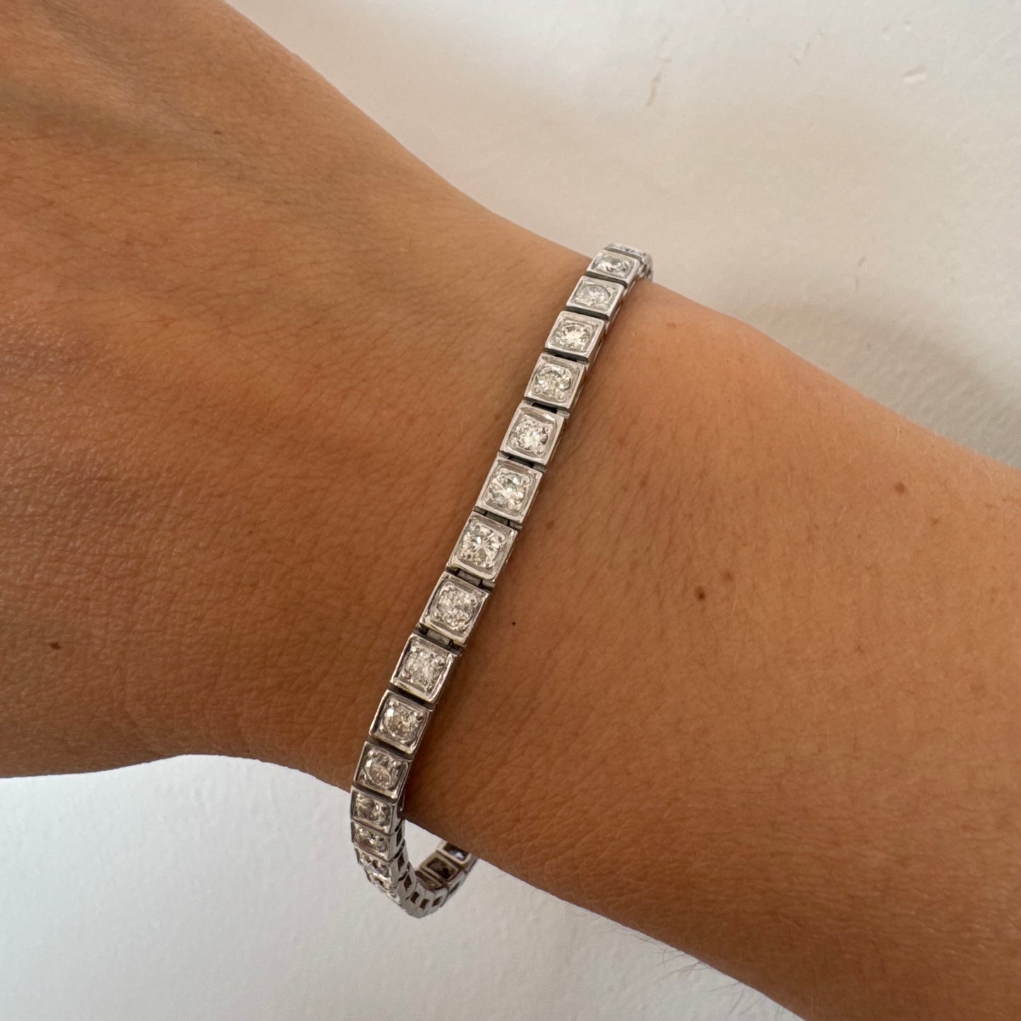 צמיד טניס זהב לבן 18 קראט משובץ יהלומים עגולים נוצצים בתוך מסגרות ריבועיות.