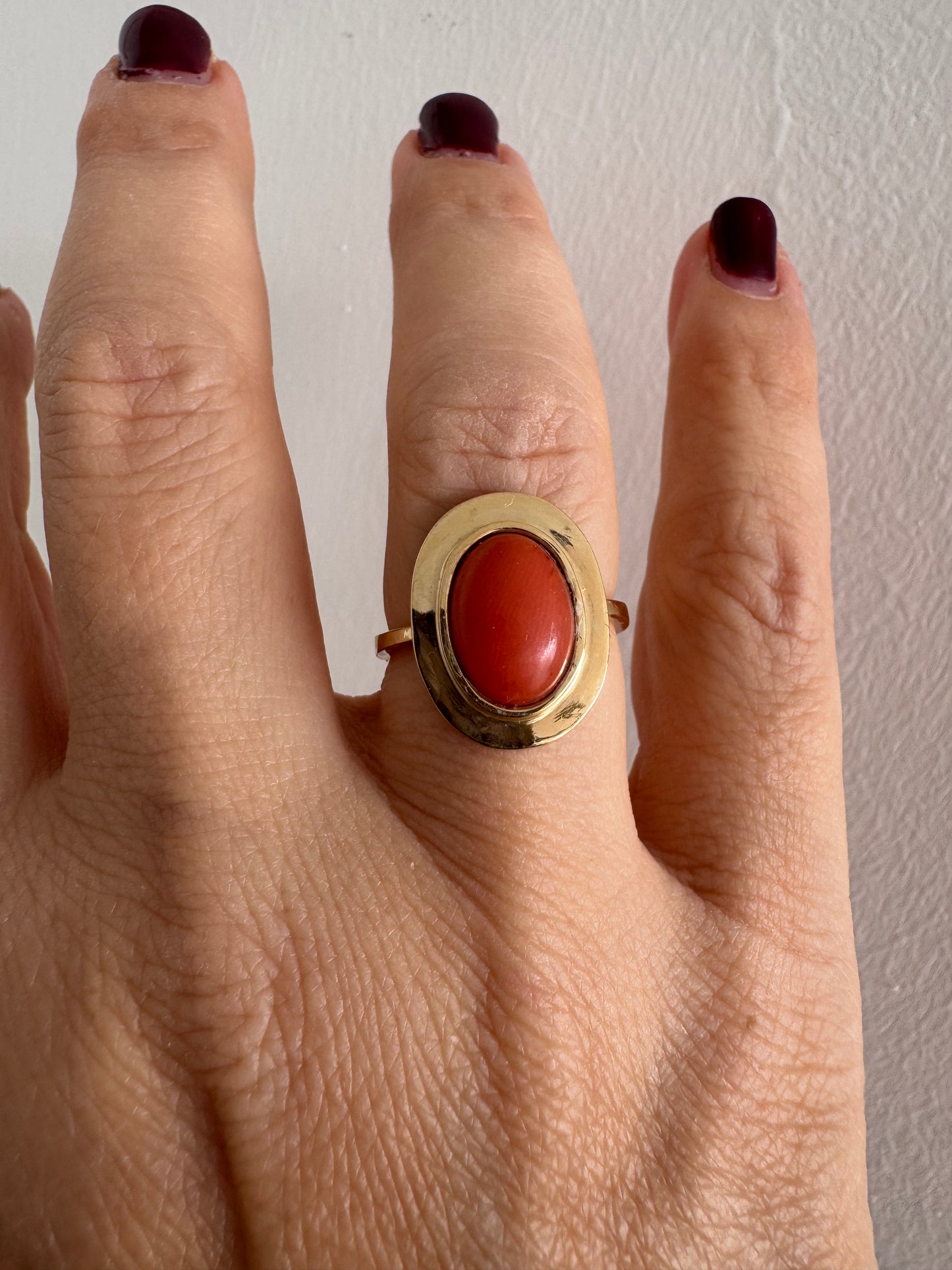 טבעת זהב 18 קראט משובצת אבן קורל אובלית בגימור קבושון, משובצת במסגרת חלקה ונקייה.