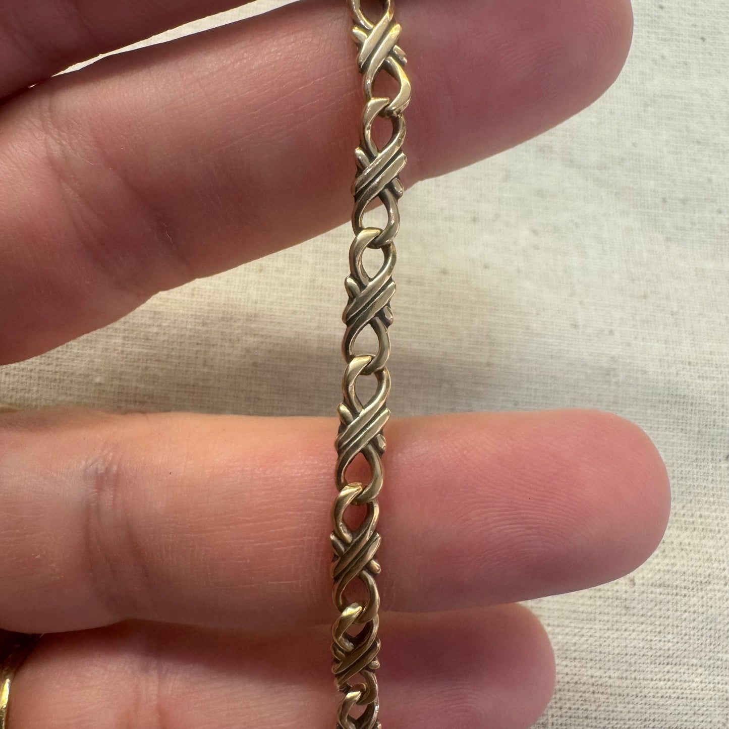 14K gold bracelet with an interwoven twisted link design and a lobster clasp closure.
