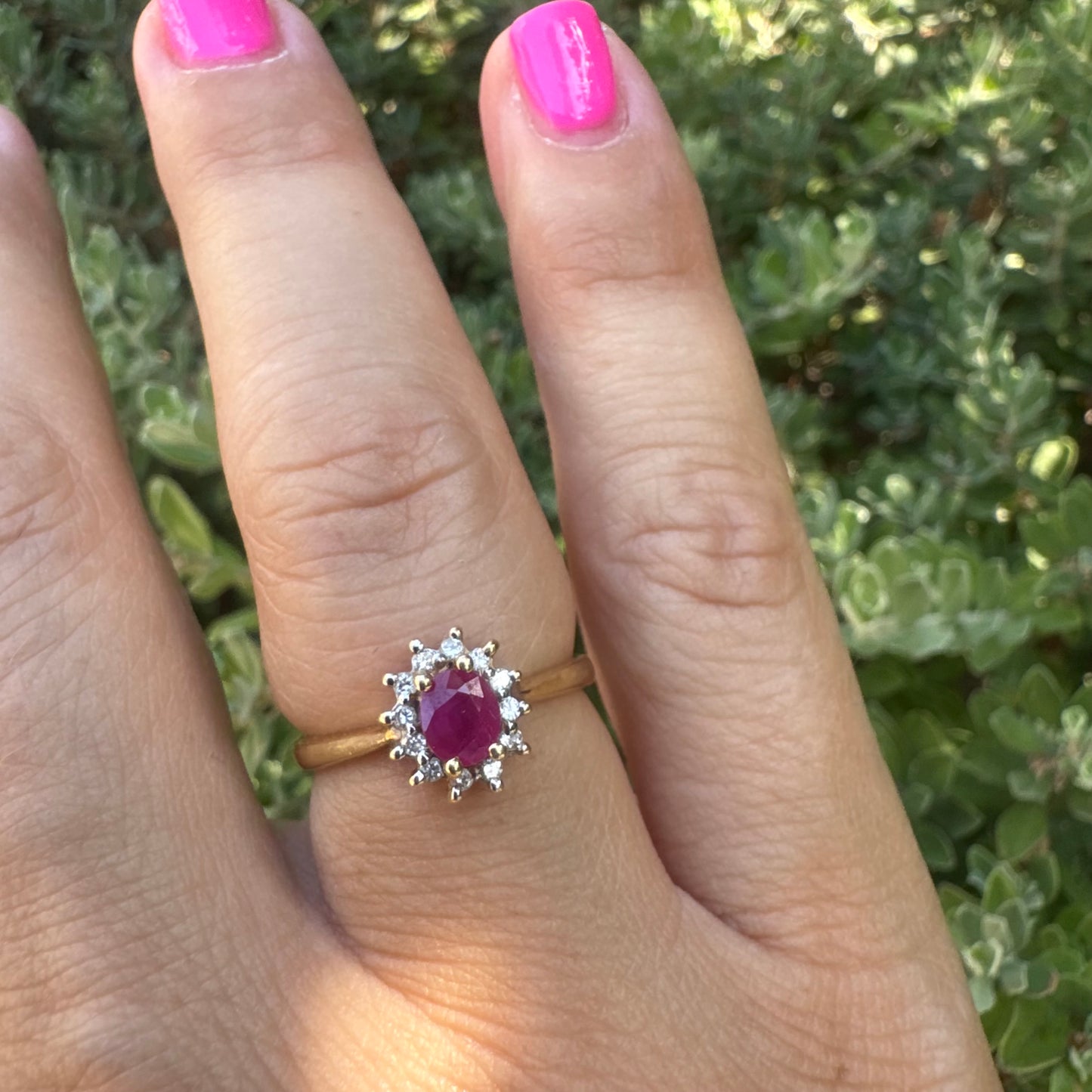 18K gold ring set with an oval Ruby at the center, surrounded by a halo of Diamonds