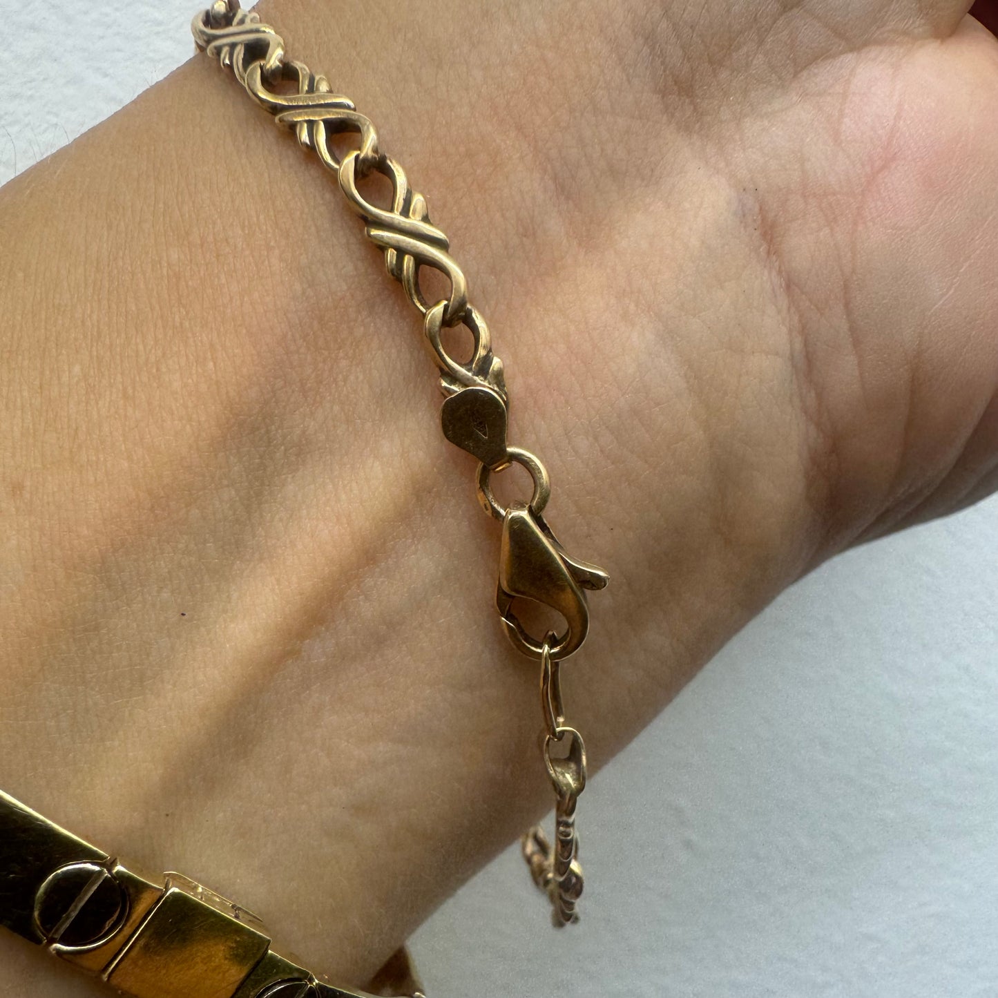 14K gold bracelet with an interwoven twisted link design and a lobster clasp closure.