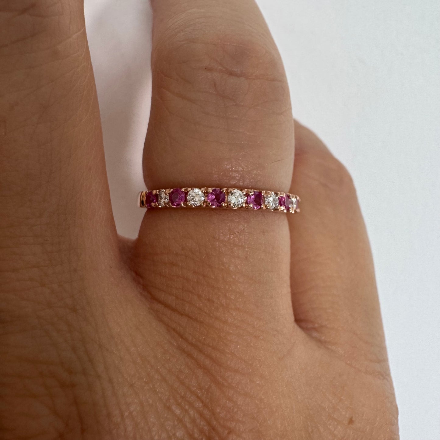 טבעת חצי איטרניטי מזהב אדום 14 קראט, משובצת ברצף של אבני רובי ויהלומים .