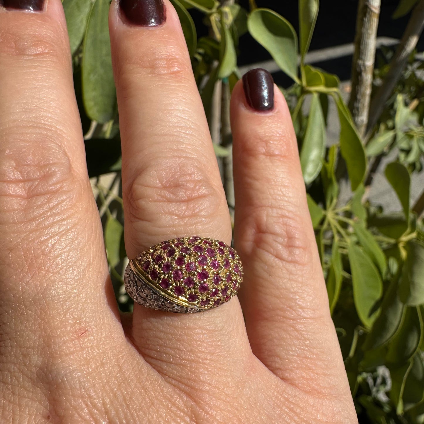 טבעת דום זהב צהוב 14 קראט ייחודית, משובצת חצי-חצי באבני רובי בצבע אדום-ורוד בוהק ויהלומים בשיבוץ פאווה צפוף.