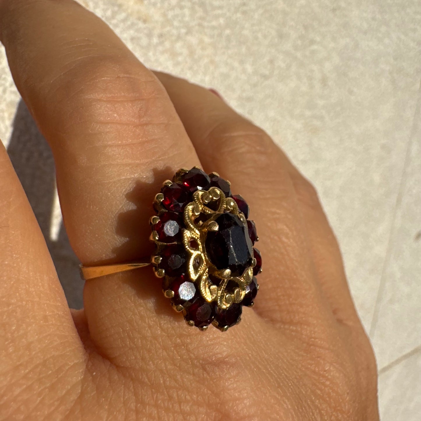 18K gold ring adorned with deep red Garnet gemstones, arranged in a radiant oval composition