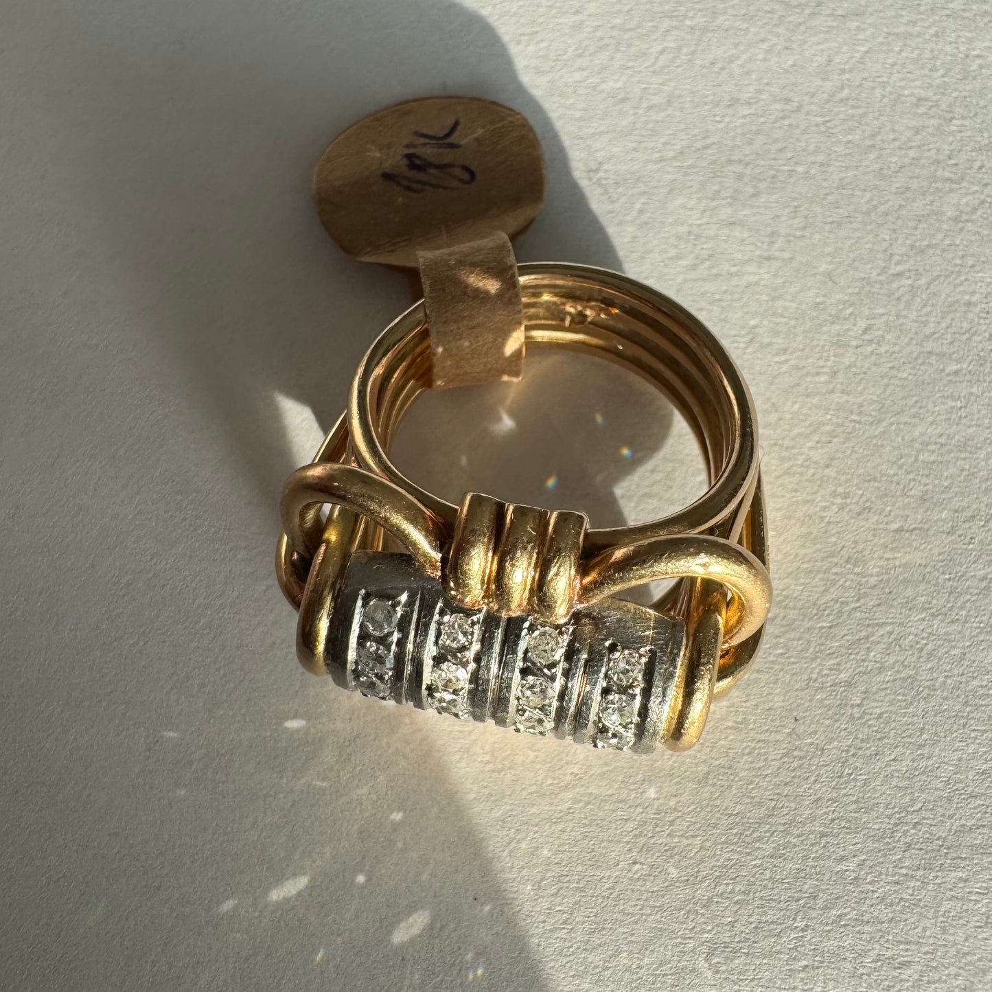 טבעת זהב צהוב ולבן 18 קראט עם מרכז בצורת חבית, משובצת יהלומים נוצצים.