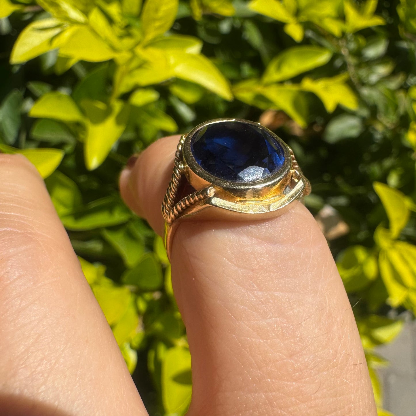 18K yellow gold ring set with a large oval deep blue Sapphire set in an ornate bezel.