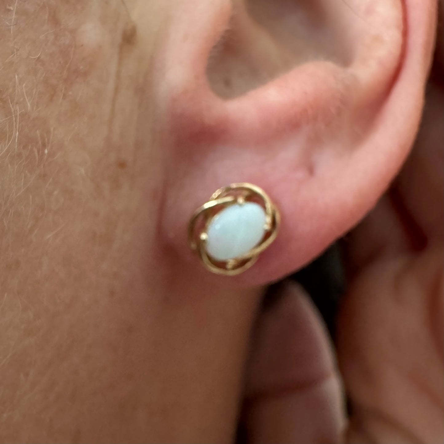 עגילי זהב צהוב 14 קראט משובצים אבני אופל אובליות בגוון לבן חלבי עם משחקי צבע טבעיים ועדינים.