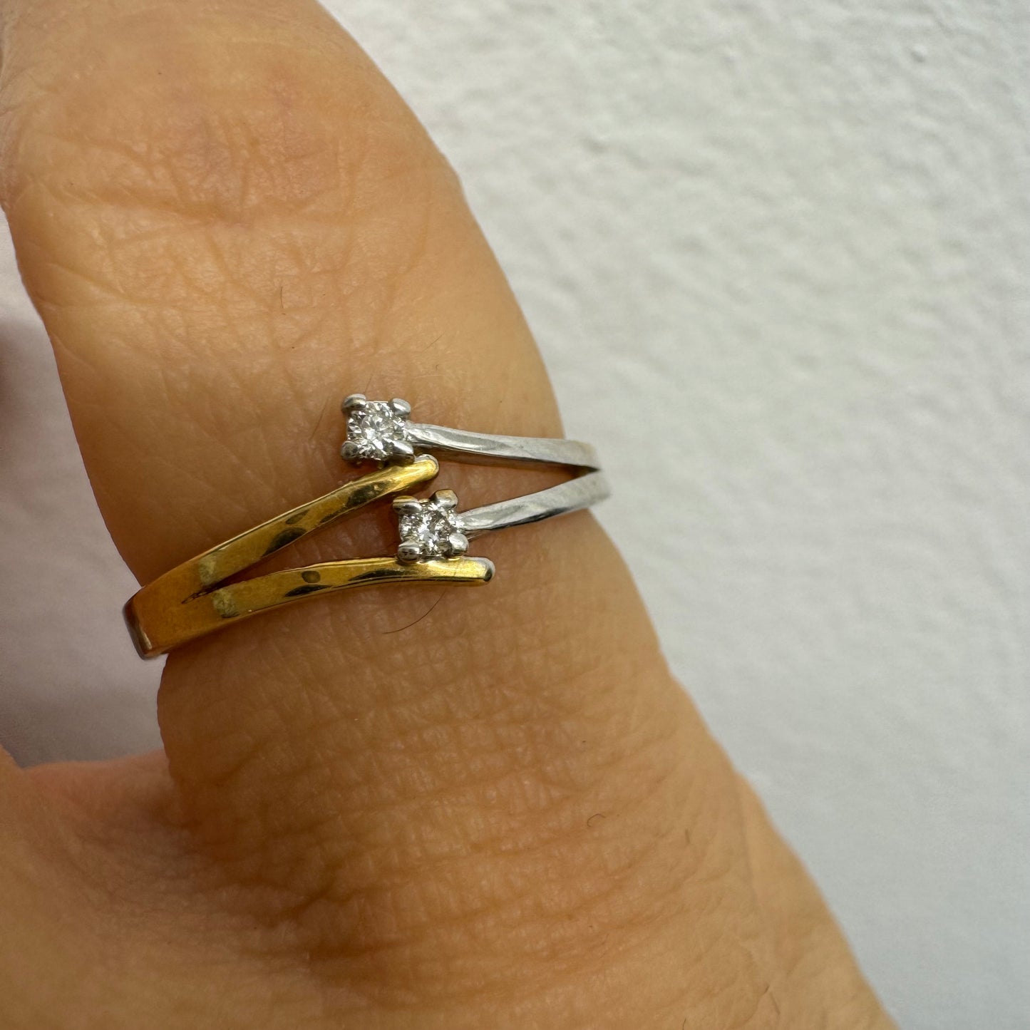 טבעת זהב 14 קראט, עם זרועות מצטלבות בזהב צהוב וזהב לבן, שכל אחת מהן משובצת יהלום קטן ונוצץ.