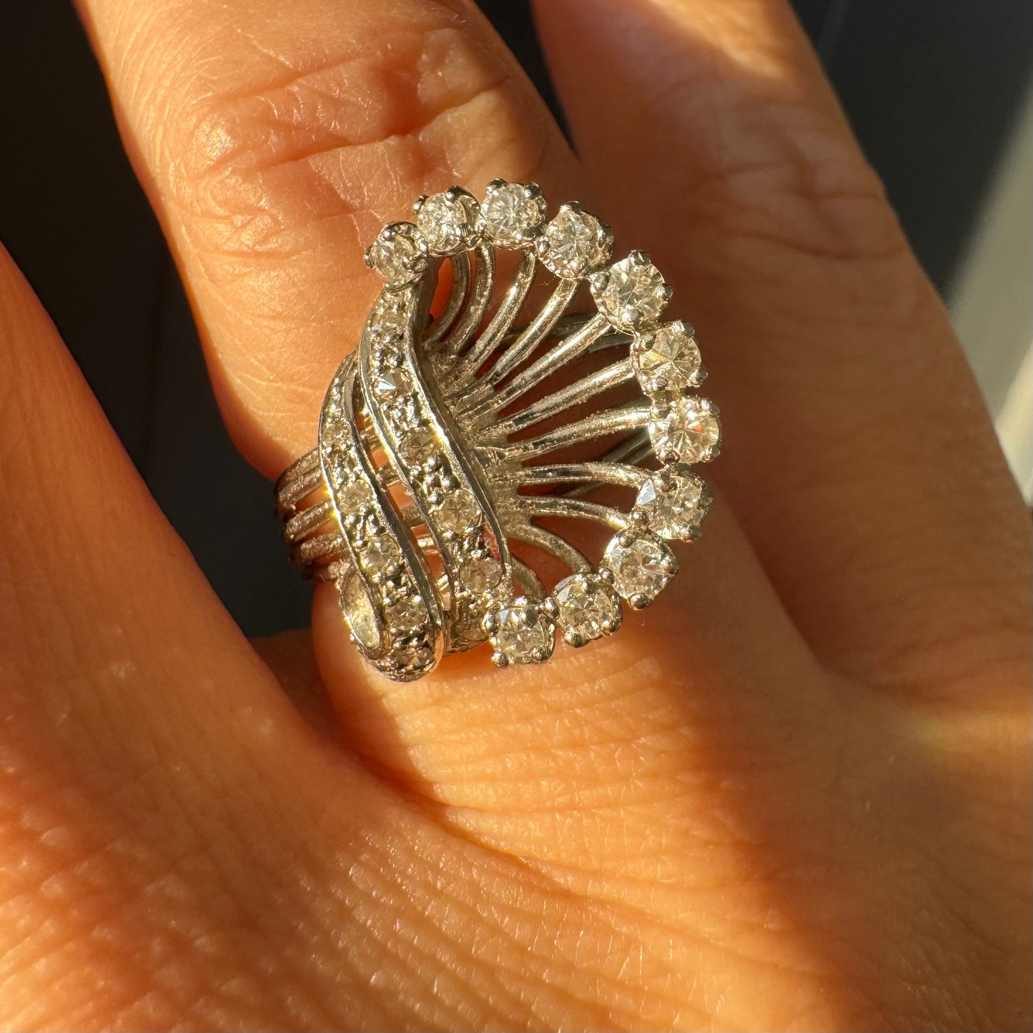 טבעת זהב 18 קראט משובצת יהלומים בעיצוב ייחודי ודינמי, עם קווים פתוחים ומניפת יהלומים היקפית היוצרת מראה עשיר ומלא ברק