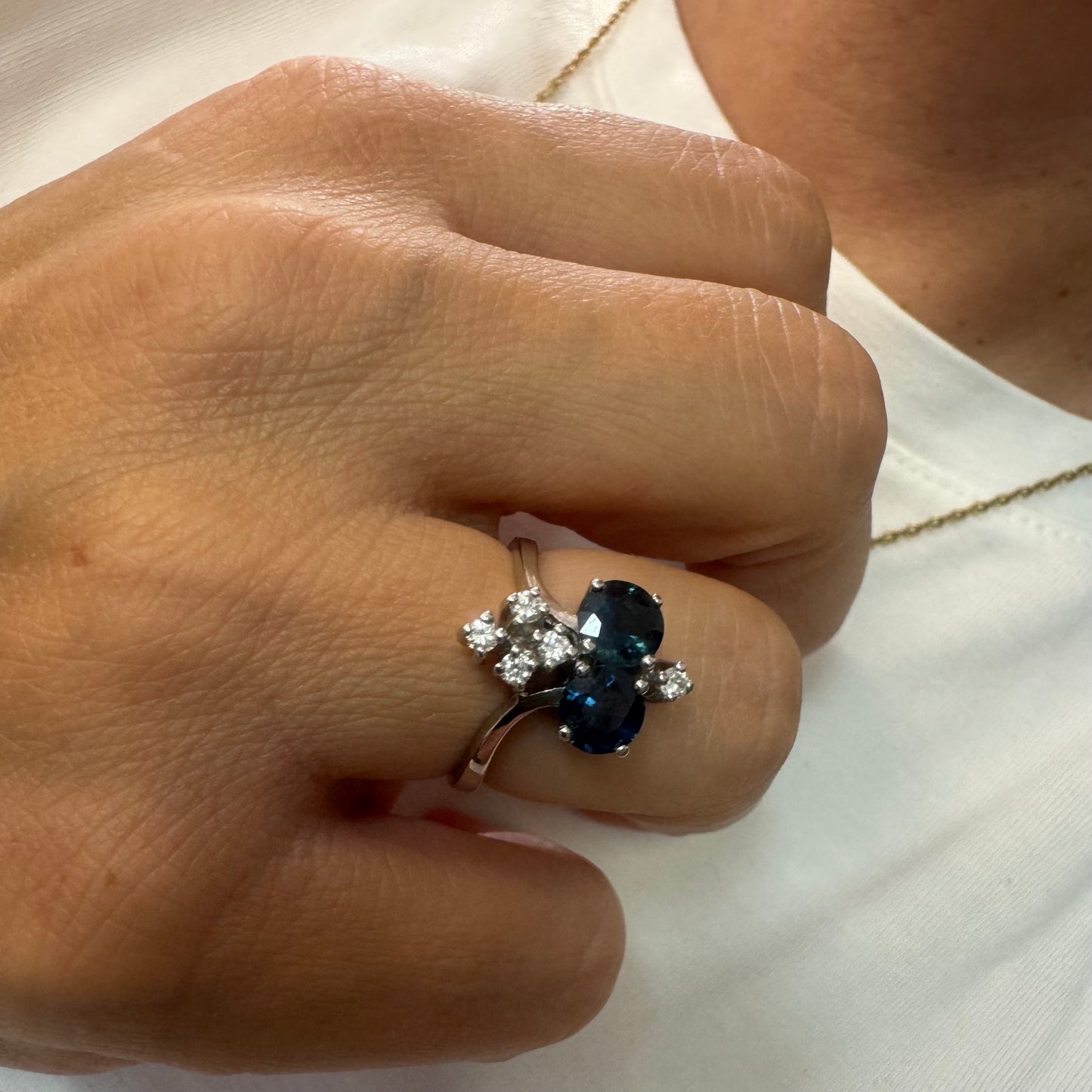 14K gold ring set with two deep blue oval Sapphires accented by clusters of brilliant white Diamonds.