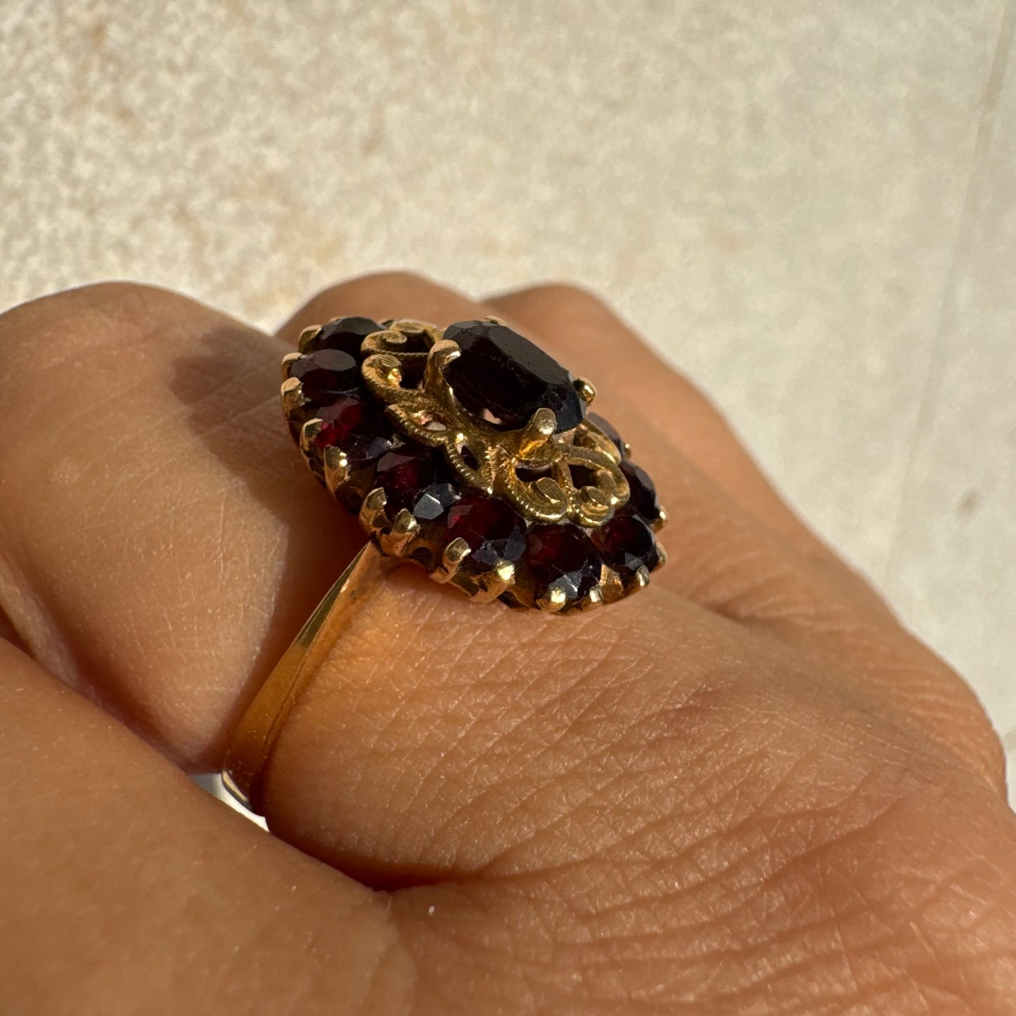 18K gold ring adorned with deep red Garnet gemstones, arranged in a radiant oval composition