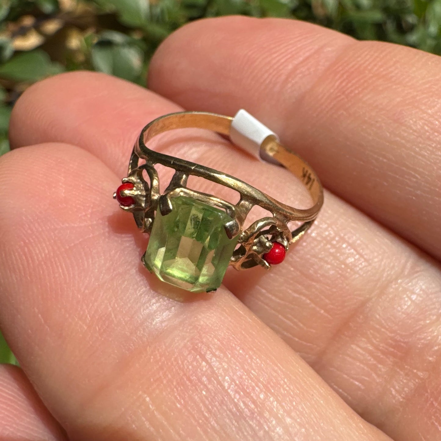 14K gold ring set with a vibrant emerald-cut Peridot at its center, flanked by two delicate red Coral accents
