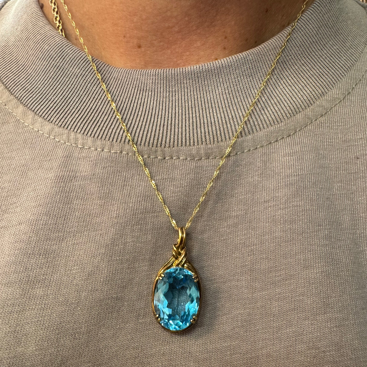 9K gold Pendant set with a striking oval-cut Blue Topaz