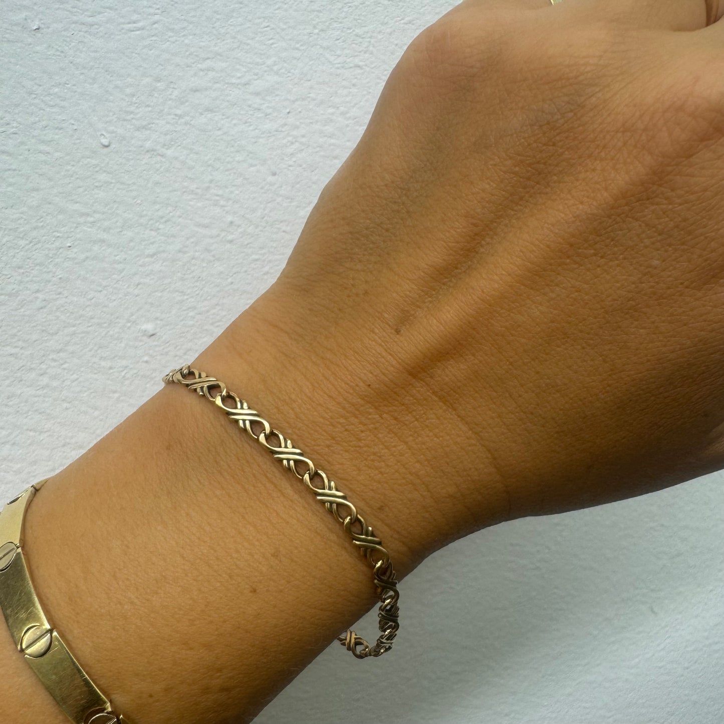 14K gold bracelet with an interwoven twisted link design and a lobster clasp closure.