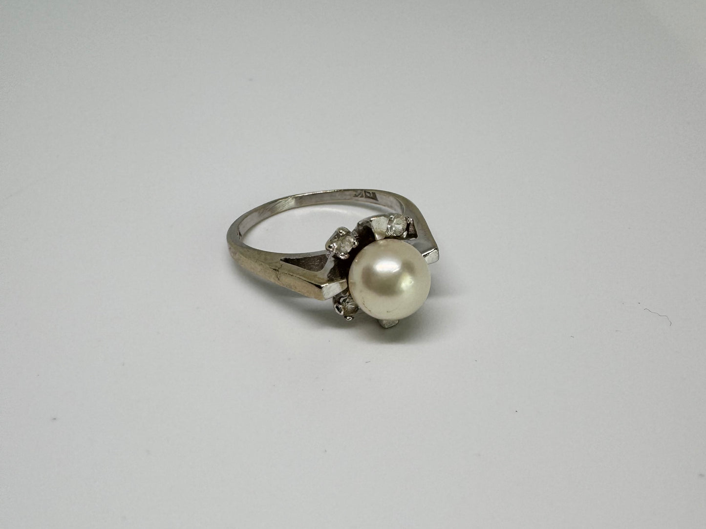 10K white gold ring set with a central Pearl surrounded by Diamonds.