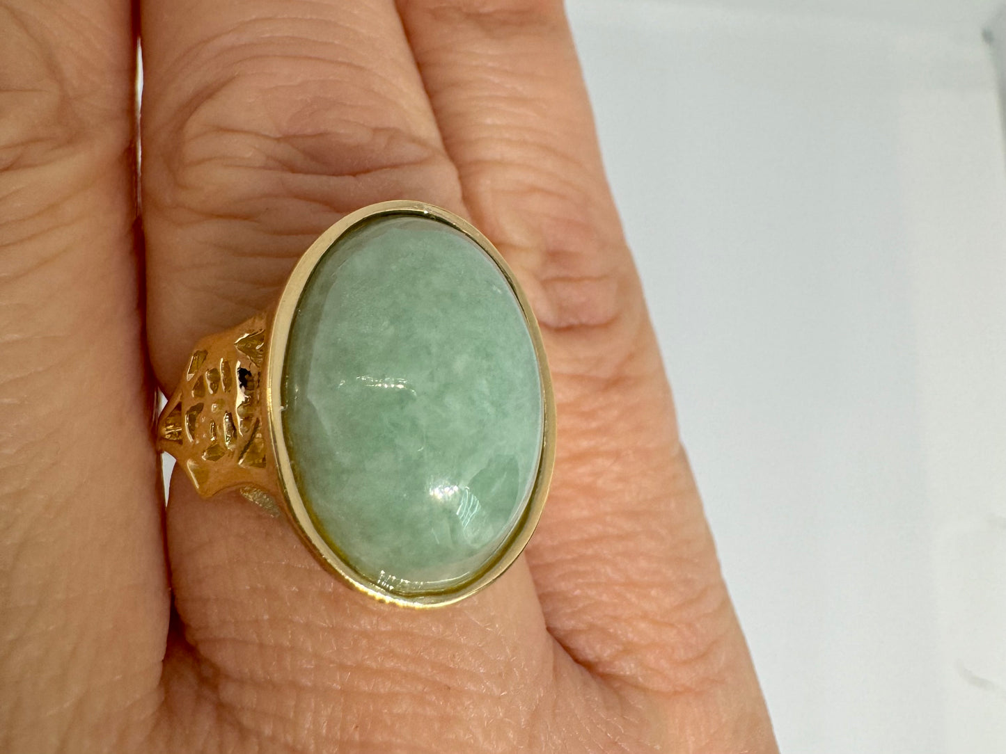 14K gold ring featuring a large oval light green Jade with a smooth polished finish, set in a classic bezel setting.