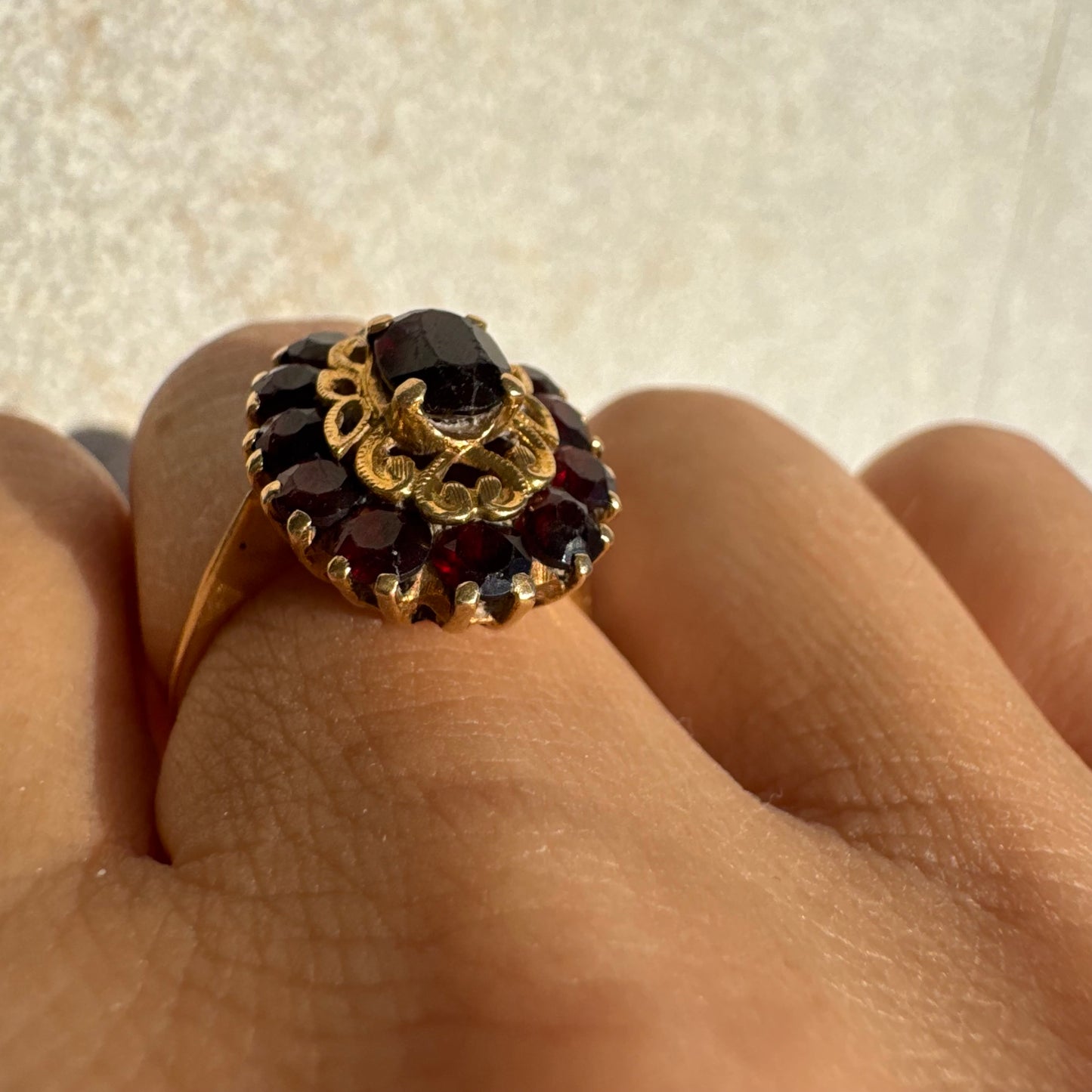 18K gold ring adorned with deep red Garnet gemstones, arranged in a radiant oval composition