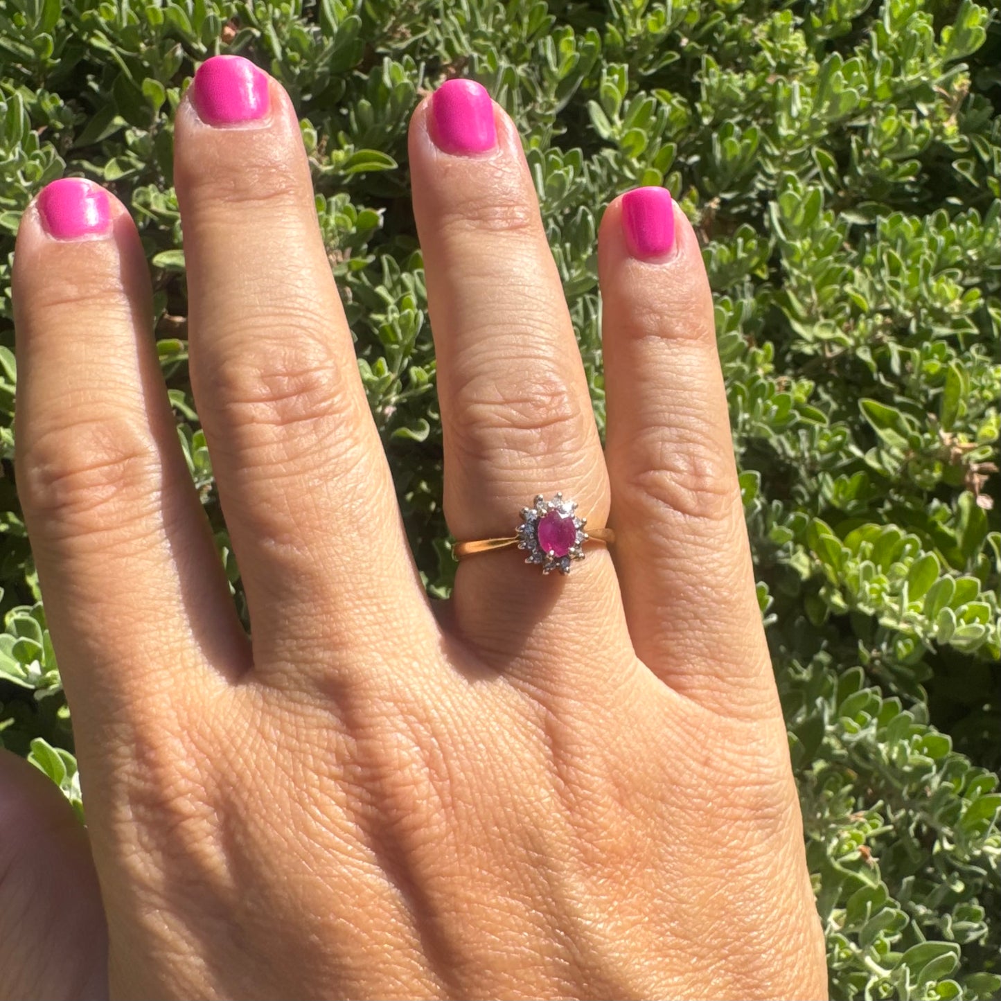 18K gold ring set with an oval Ruby at the center, surrounded by a halo of Diamonds