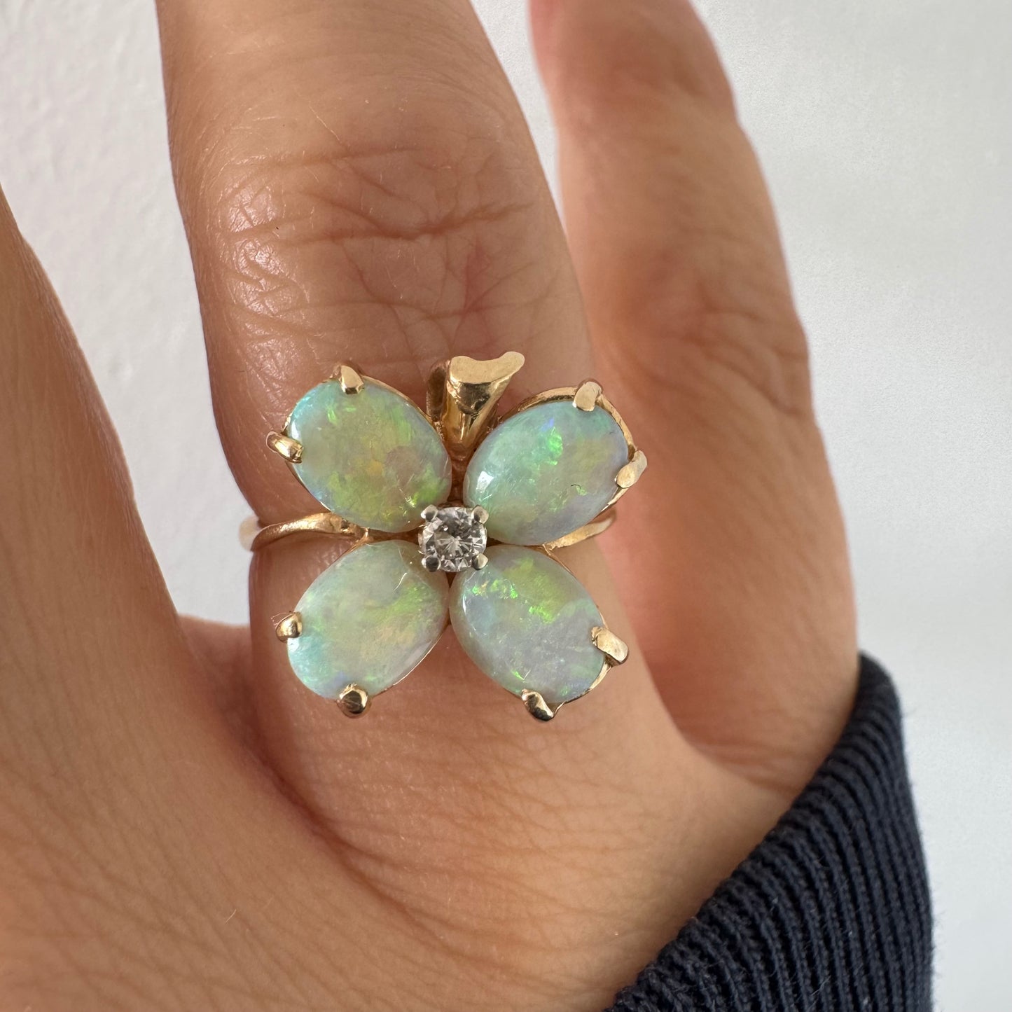 טבעת זהב 14 קראט בעיצוב פרח, משובצת ארבע אבני אופל בחיתוך טיפה ובמרכז יהלום טבעי.