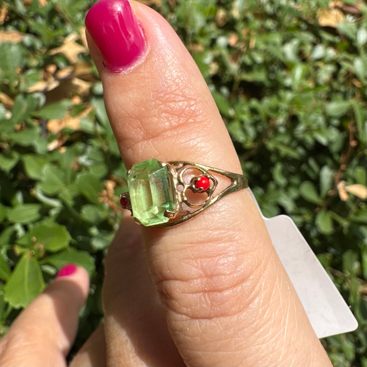 14K gold ring set with a vibrant emerald-cut Peridot at its center, flanked by two delicate red Coral accents