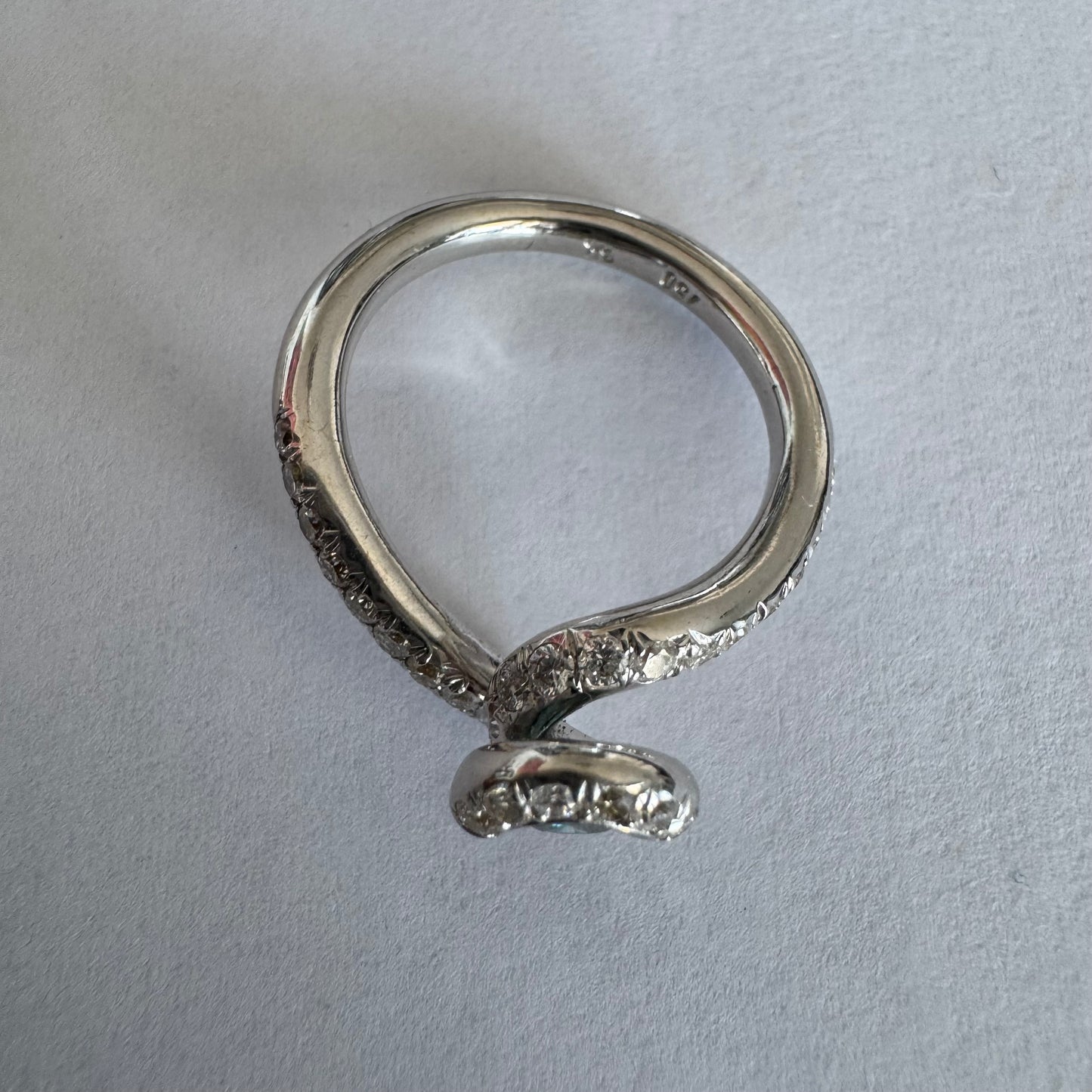 טבעת זהב לבן 18 במרכזה משובץ יהלום כחול עז, מוקף בהילה של יהלומים לבנים והזרועות של הטבעת משובצות יהלומים