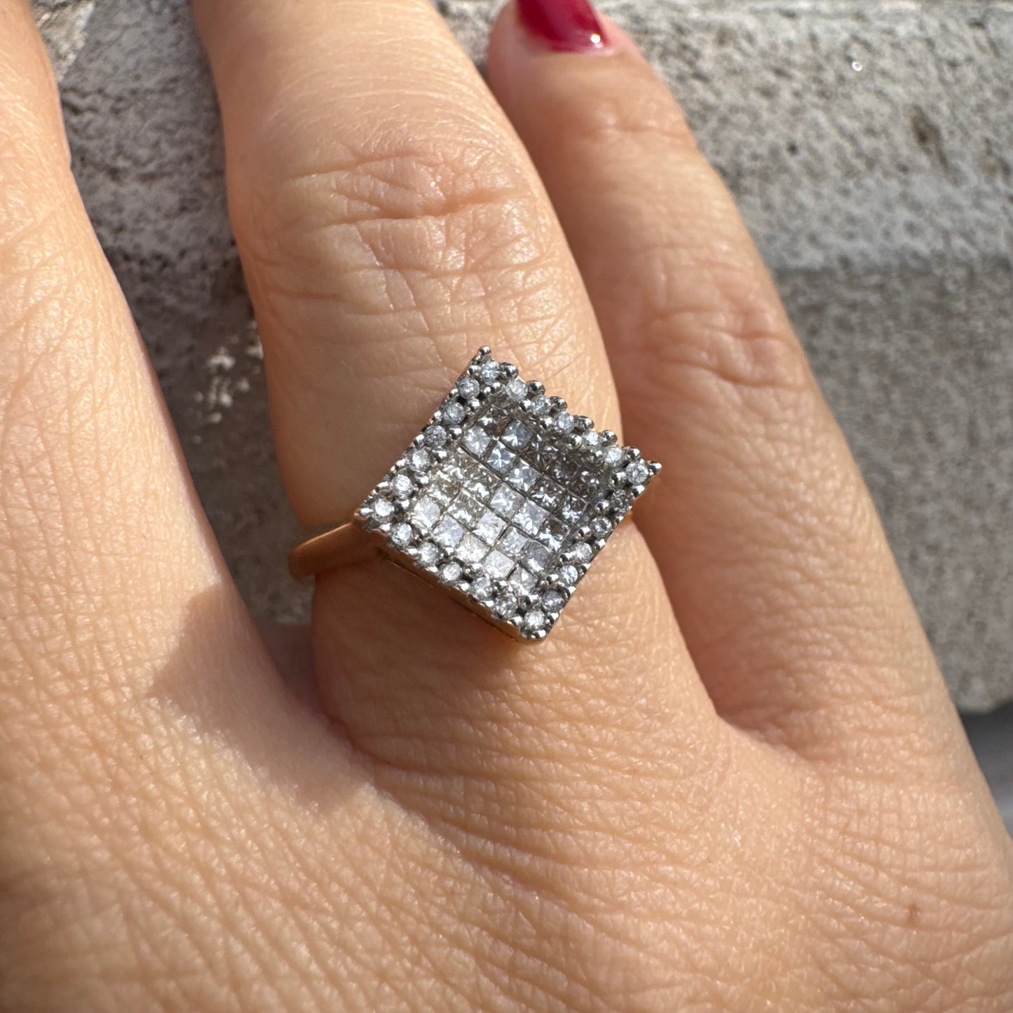 טבעת זהב 14 קראט בעיצוב ריבועי משובצת יהלומים בחיתוך פרינסס ומוקפת מסגרת יהלומים עגולים.