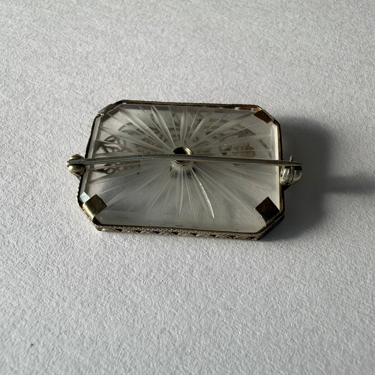 An antique Art-Deco brooch featuring a geometric design, delicate floral details & a sparkling Diamond