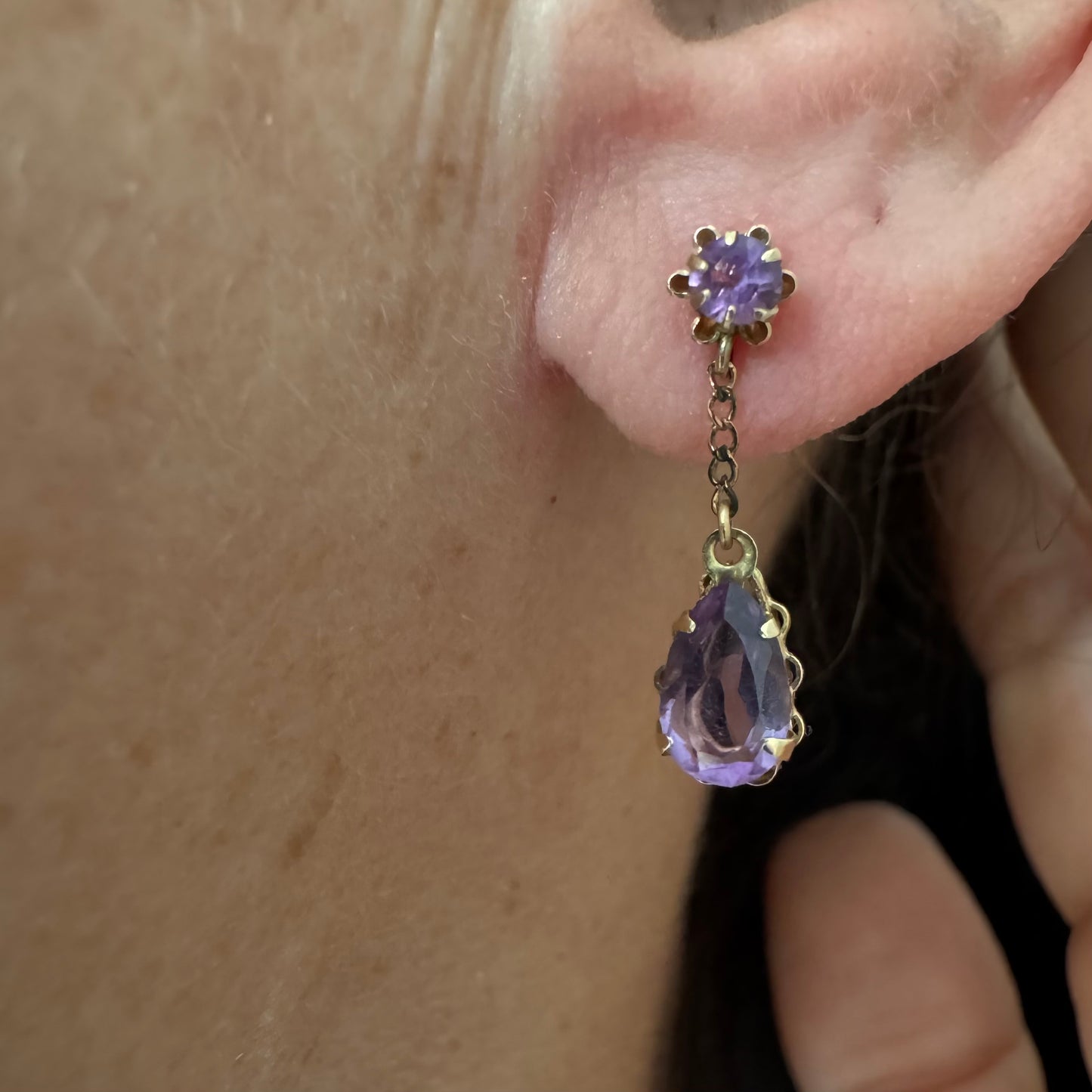 עגילים זהב צהוב 14 קראט משובצים אבני אמטיסט בגוון סגול עמוק בחיתוך טיפה, בשילוב אבן עליונה תואמת ועיטור שרשרת עדינה המחברת ביניהן.