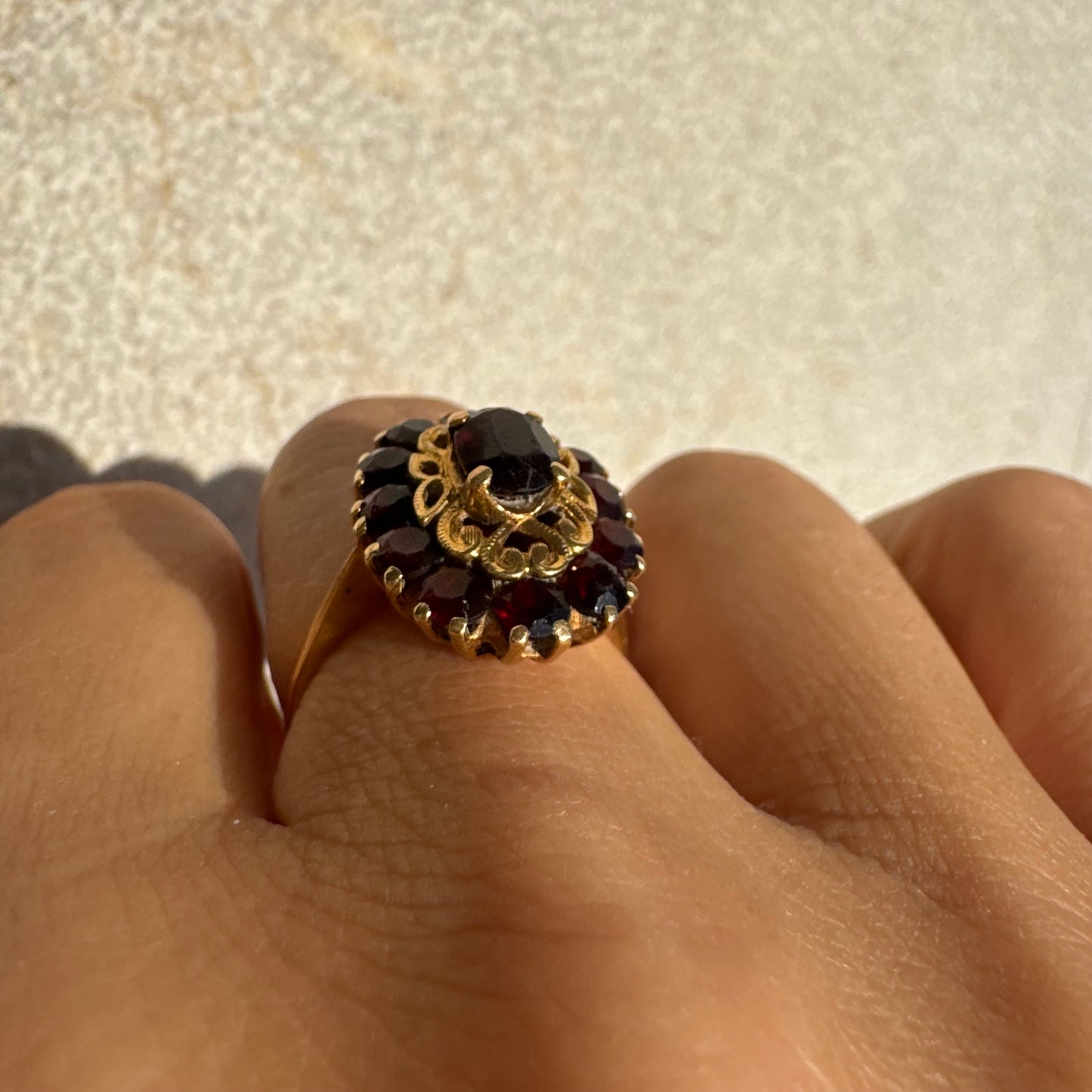 18K gold ring adorned with deep red Garnet gemstones, arranged in a radiant oval composition