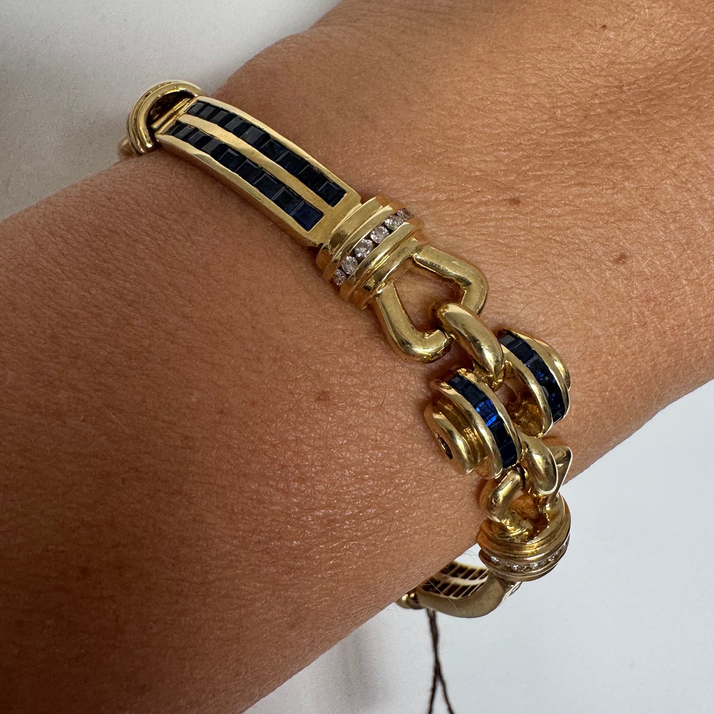 18K gold bracelet featuring a bold link design set with deep blue Sapphires and a subtle Diamond accent at the center.