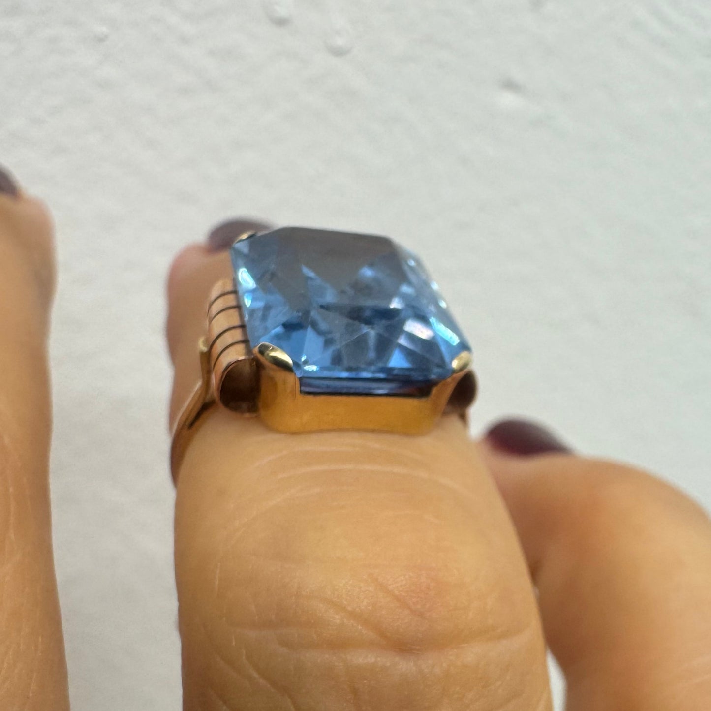 18K gold ring featuring a large rectangular Blue Topaz in a bezel setting with decorative side details.