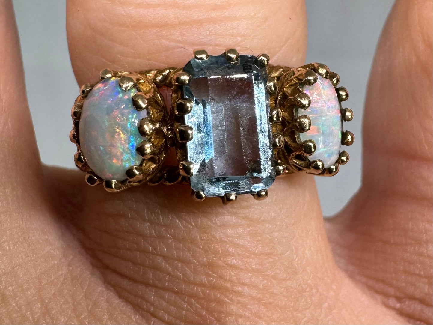 10K gold ring set with a light blue Aquamarine flanked by two dreamy Opals