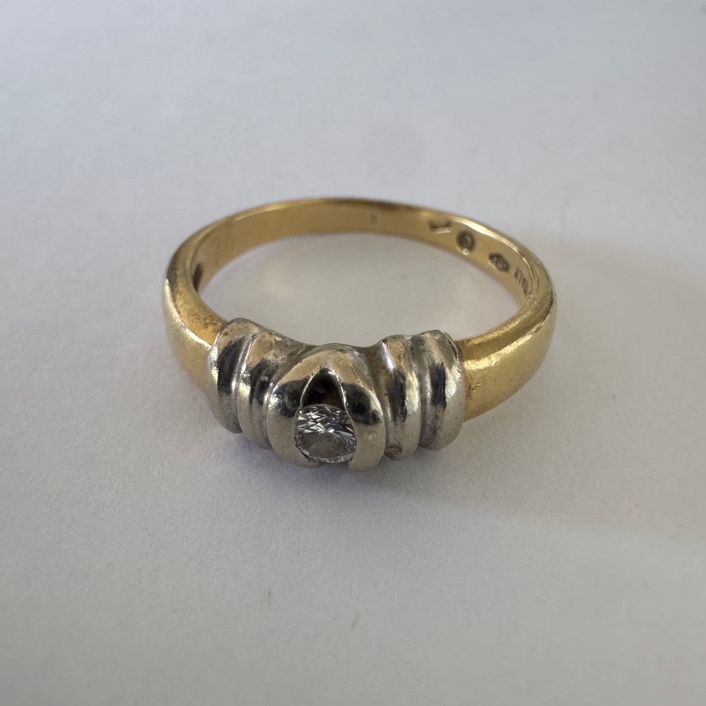 טבעת זהב 14 קראט בשילוב דו-גווני של זהב צהוב ולבן משובצת יהלום מרכזי בעיצוב נקי ומדויק.