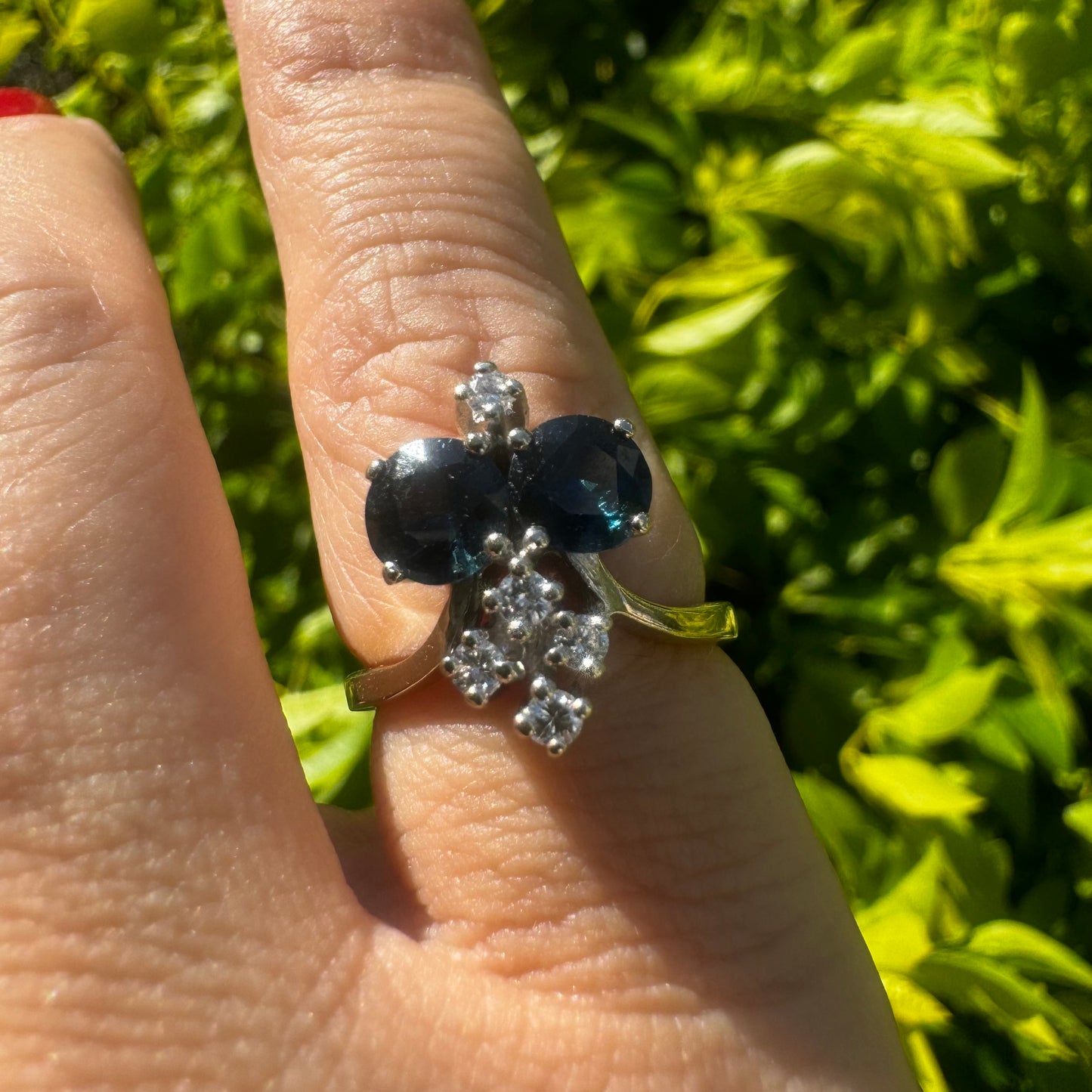 14K gold ring set with two deep blue oval Sapphires accented by clusters of brilliant white Diamonds.