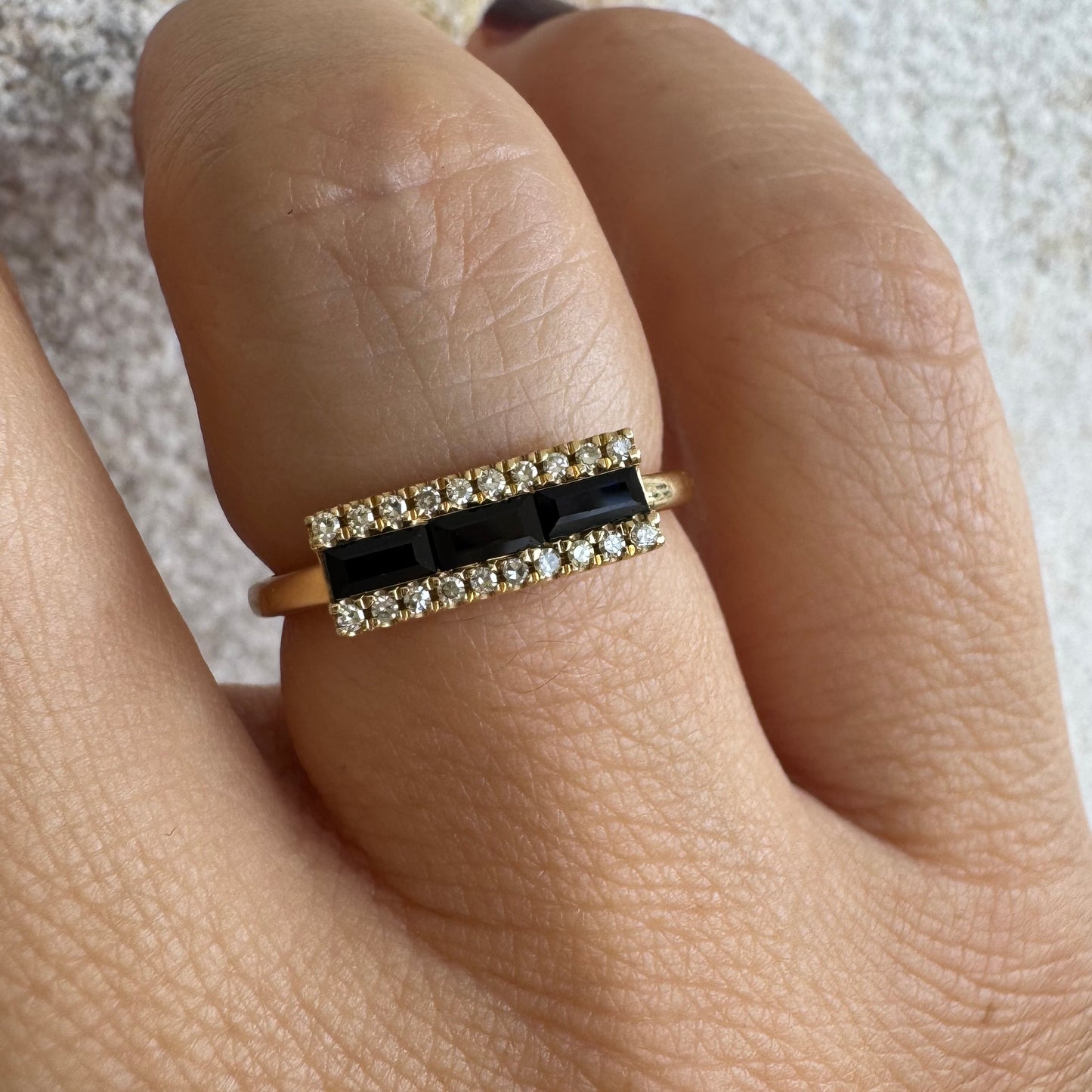 14K gold ring set with baguette-cut Sapphire framed by sparkling Diamonds