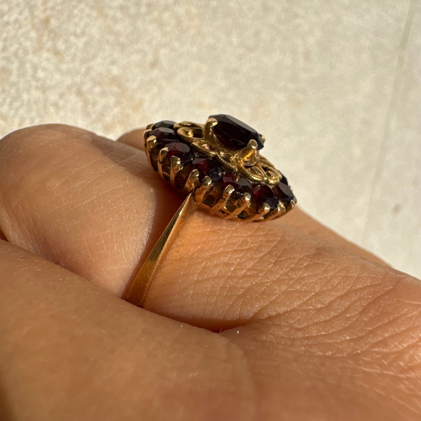 18K gold ring adorned with deep red Garnet gemstones, arranged in a radiant oval composition