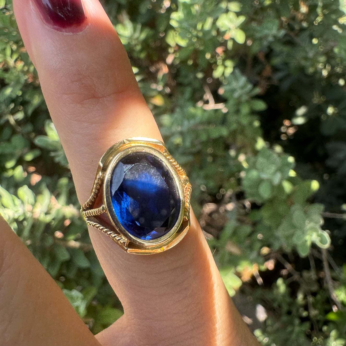 18K yellow gold ring set with a large oval deep blue Sapphire set in an ornate bezel.