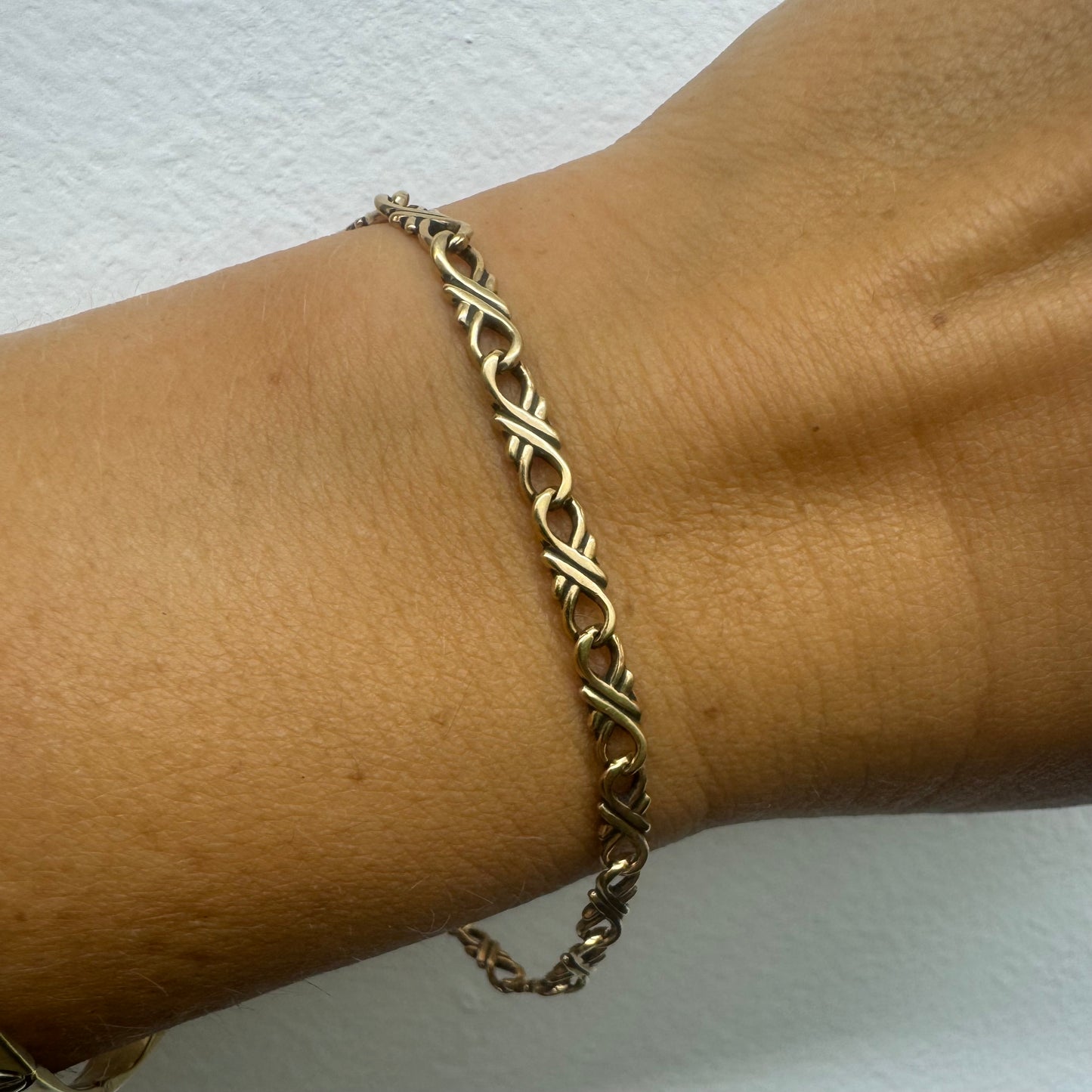 14K gold bracelet with an interwoven twisted link design and a lobster clasp closure.