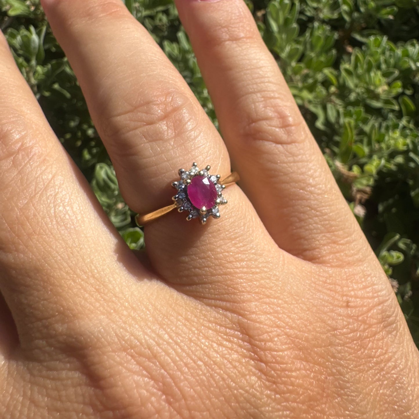 18K gold ring set with an oval Ruby at the center, surrounded by a halo of Diamonds